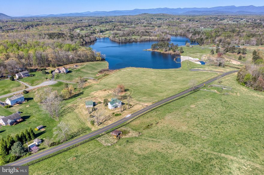 A Rare Slice of Culpeper’s History with One of Its Most Iconic Views. Opportunities like this don’t come around often. Set on just over 11 gently rolling acres, this picturesque property offers a truly breathtaking backdrop—unobstructed views of Mountain Run Lake framed by the Blue Ridge Mountains beyond. It’s the kind of view that never gets old, a postcard-perfect panorama that changes with the seasons and stirs the soul. At the heart of the property stands a 4-bedroom, 1-bath farmhouse believed to date back to the late 1800s, filled with the kind of character only time can create. Original hardwood floors run throughout the home, complemented by solid wood doors, tall baseboards, and beautifully crafted trim. Soaring 10+ foot ceilings and oversized rooms give the home an airy, gracious feel, while nearly every window captures a slice of the stunning scenery. The main level features a spacious country kitchen, a separate formal dining room, a large living room, a main-level bedroom, and a full bath. Down the hall, intricate woodwork and architectural details tell the story of a home built to last. A tucked-away back staircase leads from the upper level down into the kitchen, adding a bit of secret charm. Both the wide front porch and the quieter rear porch offer peaceful spots to soak in the views—whether it’s rolling pasture or mountain peaks you’re drawn to. Behind the main house sits a detached garage, but hidden beneath the siding lies something special: the original log walls of the first home on the property, still intact and rich with history. Whether you dream of restoring the farmhouse to its former glory, transforming it into a charming Bed & Breakfast, creating an event venue, or building the perfect lakeside getaway, this property offers endless potential. Subdivision potential with R1 zoning according to Culpeper zoning please confirm. 

Sold strictly AS-IS, this is a true diamond in the rough, waiting for someone with vision and heart to make it shine again. Come walk the land, breathe the mountain air, and let the view speak for itself—you’ll know you’ve found something rare.