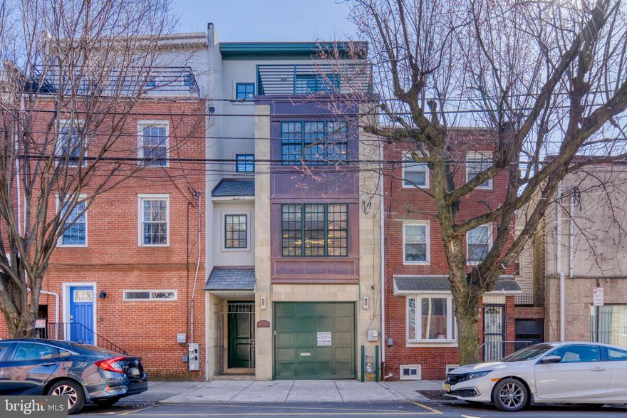 Abundant space, luxury features, and private parking in Bella Vista! 606 Christian St is a modern 4-story townhome offering 4 bedrooms, 3.5 bathrooms, and a 1-car garage in one of Philly’s most unique, highly sought-after neighborhoods. A gated, recessed entryway acts as a buffer between the home and the outside world. Inside, a tiled hallway leads to a large foyer with a coat closet, powder room, and access to the 1-car garage. Stepping down, there’s a carpeted bonus room, ideal for a media room, den, or playroom, and a separate unfinished room below with 390 sqft of storage space. Step up from the foyer and you’ll discover the stunning living room with soaring 14.5 ft tall ceilings, oversized arched windows, and beautiful hardwood floors. Anchored by a custom bookcase on one wall and a floor-to-ceiling marble fireplace on the other, natural light pours into the space giving it an open and airy feel. From the living room, there’s access to the large back patio, perfect for entertaining. This secluded oasis is sure to become your go-to spot on cool spring days and warm summer nights. Back inside, a short ascent takes you to the open kitchen and dining area. A breakfast nook with views of the living room below sits at one end and the dining area with room to accommodate a table for 8+ sits at the other. At the center of this space is the sleek chef’s kitchen adorned with white inset cabinets, Viking Professional stainless steel appliances, granite countertops and a designer backsplash. On the home’s third level, there are two secondary bedrooms with hardwood floors, a full hall bathroom and a conveniently placed laundry room. A spacious bedroom suite with oversized windows and an attached full bathroom complete this level. The home’s top level is dedicated to the primary suite. The huge bedroom has a fireplace, a kitchenette with GE Monogram appliances and a walk-in closet. A balcony off the bedroom offers views of the city and holiday fireworks displays at Penn’s Landing. The serene, spa-like ensuite is encased in marble from the jet soaking tub to the glass-enclosed shower and double vanity. In addition to all this home offers inside, its location is a walker’s paradise with a Walk Score of 98. The legendary 9th Street Italian Market is steps away with exciting new additions such as Biederman's and Mark Vetri's Fiorella that are even closer or grab a coffee from Shot Tower Coffee right across the street! Take a 5-minute walk to enjoy Star Garden or Palumbo Park, though many other options nearby. Nearby shopping on South Street includes Whole Foods, Wine & Spirits, and Jim's Steaks. This central location also provides easy access to Washington Ave, Broad St & I-95.
