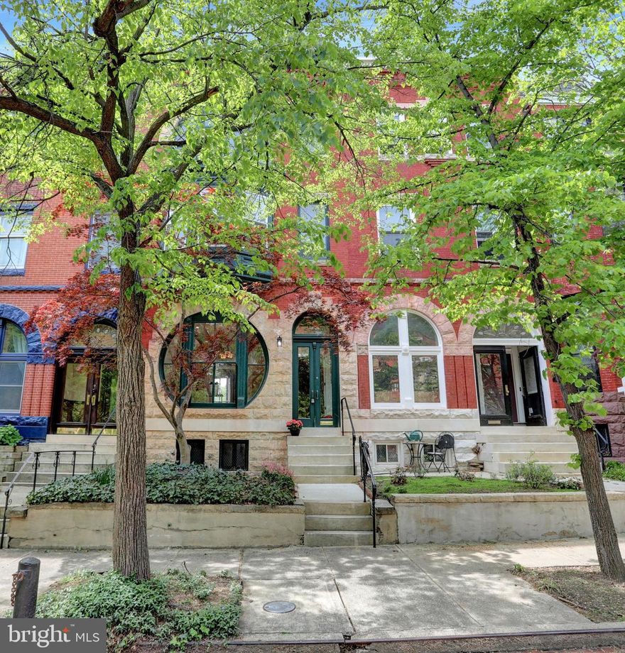 Welcome to this exceptional Bolton Hill property, where historic Baltimore charm meets modern luxury in the heart of the sought-after Bolton Hill neighborhood. This one-of-a-kind home blends grand 19th-century architecture with high-end contemporary finishes, creating a truly special place to call home. The distinctive façade is an instant showstopper, featuring original red brick paired with robust stonework and dramatic, oversized arched and circular windows. Lush front landscaping, mature trees, and an elevated entry with wrought-iron railings complete the picture, while the tree-lined street creates an inviting, walkable community atmosphere. Step inside to experience expansive living spaces adorned with tall ceilings, beautiful hardwood floors, and period millwork. The formal living and dining rooms flow gracefully together—ideal for entertaining—with historic mantels, tiled fireplaces, and classic pocket doors offering both character and flexibility. The kitchen is a chef’s dream, fully renovated with white shaker cabinetry, high-end stainless appliances, subway tile backsplash, and a custom wood range hood. A center island with quartz countertop is perfect for meal prep and casual dining. The second and third floors offer incredible versatility for modern living. The third-floor primary suite is a true retreat: spacious and sun-drenched, featuring a dramatic set of arched windows, a large walk-in closet/dressing room, and a spa-inspired bath with double vanities, a marble shower, and built-in bench seating. Secondary bedrooms are generously sized, bright, and include ample closet space. A charming bay window with a built-in bench in one bedroom offers the perfect reading nook overlooking the leafy street. Schedule your private showing today and discover the magic of Bolton Hill living!