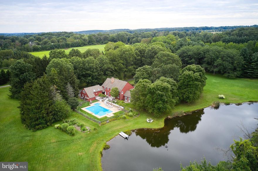 Residing in prestigious Carversville; this idyllic luxury estate is a lesson in extraordinary living. Nestled within a serene setting on a private road, the supremely private 11.19 acres are enhanced by natural topography that has been crafted to create exceptional outdoor living space providing entertainment perfection.  The park like setting features a pond with a dock, gated in-ground pool, full size pickleball court, plush lawns and professional landscaping enhanced with exquisite seasonal flowers. Offering the convenience of newer construction while capturing the romance and sophistication of stately farmhouse structures, Michael Stohler's premier custom build of over 5,400 square feet of living space features wide plank white oak floors, rich moldings, exposed beams, palladium windows, Mercer tile in all five creative bathrooms, and three noble fireplaces. The grand scale of the two-story foyer is complimented by the distinctive living and dining rooms with vaulted beam ceilings and an architectural balustrade.  Extraordinary custom pickled-pine shaker cabinetry by William Draper enrich the chef's kitchen featuring a large center island, six burner gas stove, and large dining and sitting room with a walk-in wood burning fireplace and panoramic views of the rear ground. A vaulted sundrenched great room, handsome library, one full and one-half bath, and laundry room also grace the first level. The second level is equally impressive hosting four generously sized bedrooms and three full bathrooms. Double doors lead to the sizable master suite with fireplace, two walk - in closets (one a hidden gem) and spa bath. A separate staircase from the main level, leads to an au-pair/guest suite awaiting your finishing touches. Magnificent in purpose and size, the lower level provides ample storage and a utility/work room. Horses are permitted, stables require a hundred foot setback. Exceedingly private and exceptionally convenient to New Hope Boro - home to riverside dining & theatre, Doylestown, Philadelphia, Princeton and NYC; 4072 Thisal Lane is the embodiment of Bucks County cultured elegance wrapped in modern luxury.