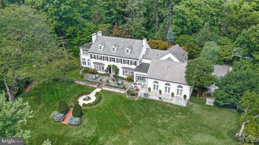 It is a rare pleasure to encounter such a property, renowned for its enduring beauty and its unexpected location with the home tucked away on nearly eight pristine acres in the heart of the Christmas City. The very essence of elegance is evidenced at first approach along a picturesque driveway lined with stately sycamores. The home is prominently positioned far from the road and is enveloped by mature trees and shrubs, manicured lawn and perennial gardens.
    The sophisticated and timeless design of this distinctive 1930’s estate home has transitioned over decades to a stunning, modern-day treasure. Painted brick, black shutters and a slate roof enhance the distinguished exterior. A bucolic setting of nature at its best is visible from most every room, and frames the main house, which is filled with natural light. 
     A handsome entry foyer has Venetian stucco walls and leads to a floor plan incorporating grand rooms for entertaining and quiet and comfortable rooms for everyday living. The formal living room is highlighted with oak floors, crown molding, built in bookshelves and a wood burning fireplace … one of five throughout the home. Tall windows showcase the flagstone patio and the outdoor living spaces beyond. The gourmet kitchen and adjacent caterer’s kitchen blend beauty and efficiency with 2020 stainless appliances, custom cabinetry, a Travertine marble floor and breakfast area with a wall of windows. Steps away, the sun-filled great room is an architectural masterpiece which features three sets of French doors providing patio access, and a soaring ceiling supported by antique chestnut beams. 
    Gracious and elegant, the primary suite pampers with a fireplace, dressing room, and a stunning and luxurious bath, befitting the pages of a designer magazine, appointed with a steam shower and soaking tub. Front and back stairways provide access to five additional bedrooms, two with en suite baths, great storage, and built-ins. The second floor laundry is particularly convenient. In the lower level are an incredible 2,000 plus capacity temperature-controlled wine cellar and a recreation room with billiard area, fireplace, and paneled wood walls.
    The outdoor surroundings are a joy. Colorful songbirds and hummingbirds visit feeders and three water features complement the serene space. Dogwoods, beeches, magnolias and maples thread the acreage and a grove of sycamores, planted in classic linear array pattern, rests behind a heated, in ground swimming pool. The smartly equipped pool house is an inviting gathering area with a herringbone brick floor, kitchen and wet bar, media closet, and two changing rooms with showers. A shaded tennis court stands ready for a set or two. Two parking courtyards, a three-car attached garage, one bay equipment garage, and six home heating and three home cooling zones are important features for a property of this scale.