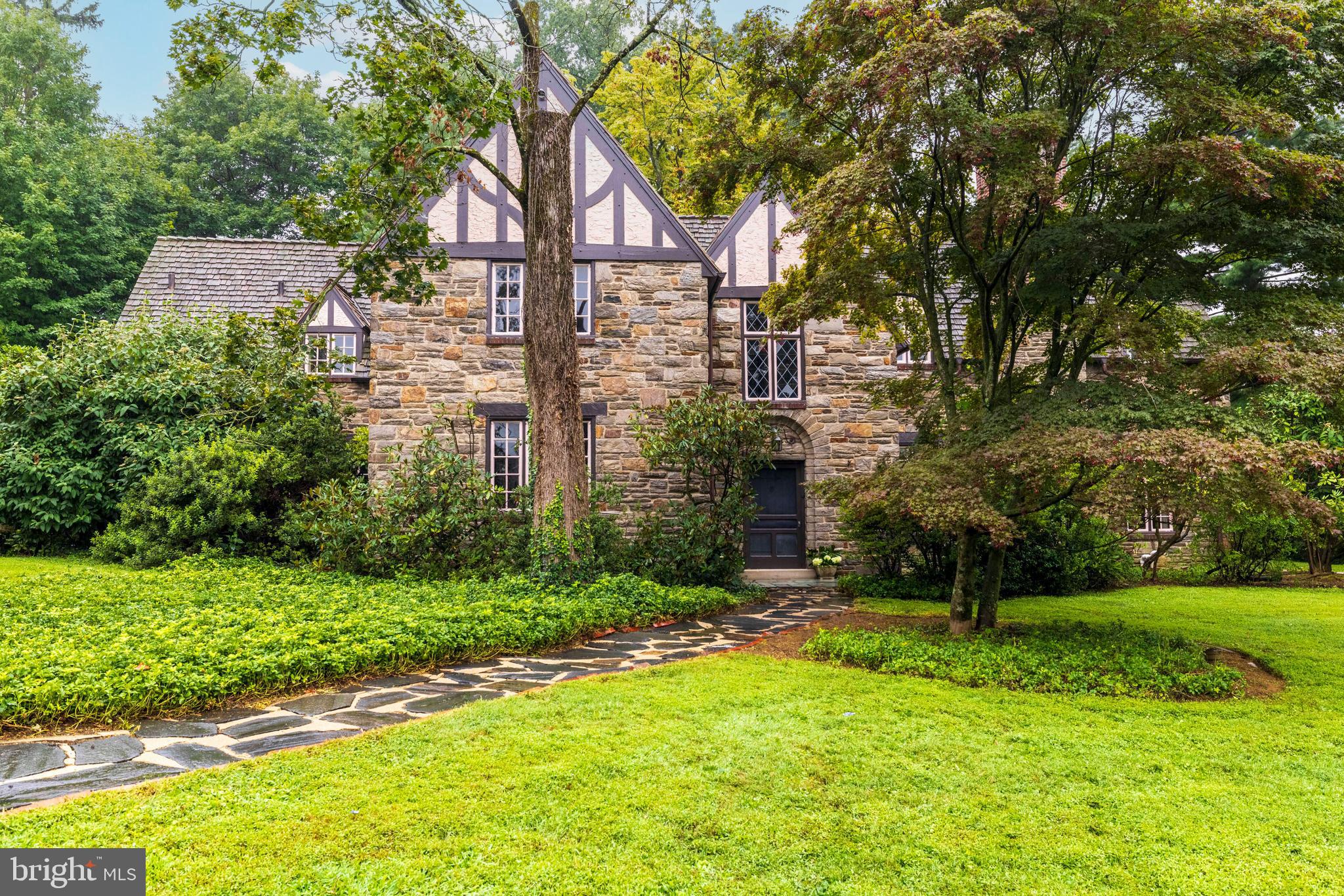 Nestled on over a half of an acre in sought-after Rydal, this spacious and architecturally rich home offers timeless character and modern potential. The stone façade with decorative timbering opens to a graceful two-story foyer with original random-width wood floors and a beautiful spiral staircase. The expansive living room boasts numerous casement windows, French doors to the grounds, and a fireplace with a beautiful wood mantel and tile surround. A formal dining room provides an ideal space for entertaining. The kitchen includes a traditional beamed ceiling, brick floors, an adjacent breakfast room, and a walk-in pantry. The charming library and a powder room complete the first floor. The exquisite open, curved staircase leads to the spacious primary suite, which features a bowed window wall, sitting room, and tiled en-suite bath. Four additional well-sized bedrooms and two additional full baths offer ample space for family and guests. A bonus room can serve as an office or sixth bedroom. Additional features include an elegant stone patio and a three-car garage. Highly rated Abington schools are a plus. Located just minutes from the Rydal Train Station, with easy access to Center City, major routes, and local shopping and dining. A home full of history, charm, and potential — an incredible opportunity to restore a classic Tudor to its original grandeur.