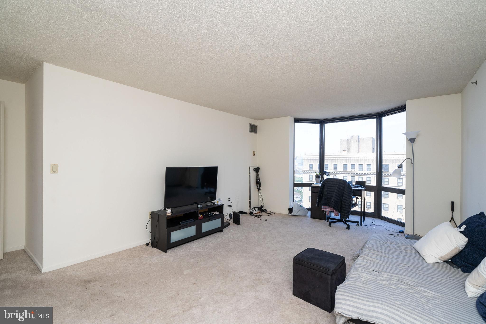 Bright and sunny one bedroom, one bathroom home at The Wanamaker House. There is an open kitchen that overlooks the living area and is lined with tile floor, white cabinetry, white countertops, and black/white kitchen appliances. The comfortably sized living/dining area is drenched with sun from large floor-to-ceiling bay windows showcasing gorgeous city views. The primary bedroom has the same floor-to-ceiling windows located in the living area, and has access to a large walk-in closet, as well as an ensuite bathroom. The bathroom is also accessible via the common area, and has white tile, a white vanity, and a shower/tub combination. The Wanamaker House is located one block from Rittenhouse Square and provides easy access to both Center City and University City; residents enjoy a 24-hour doorman, a seasonal rooftop pool, a fitness center, and a parking garage available for an additional fee (subject to availability). All common areas were recently renovated including the lobby, hallways, meeting room, amenity lounge, and fitness center, designed by world- renowned architect Cecil Baker.