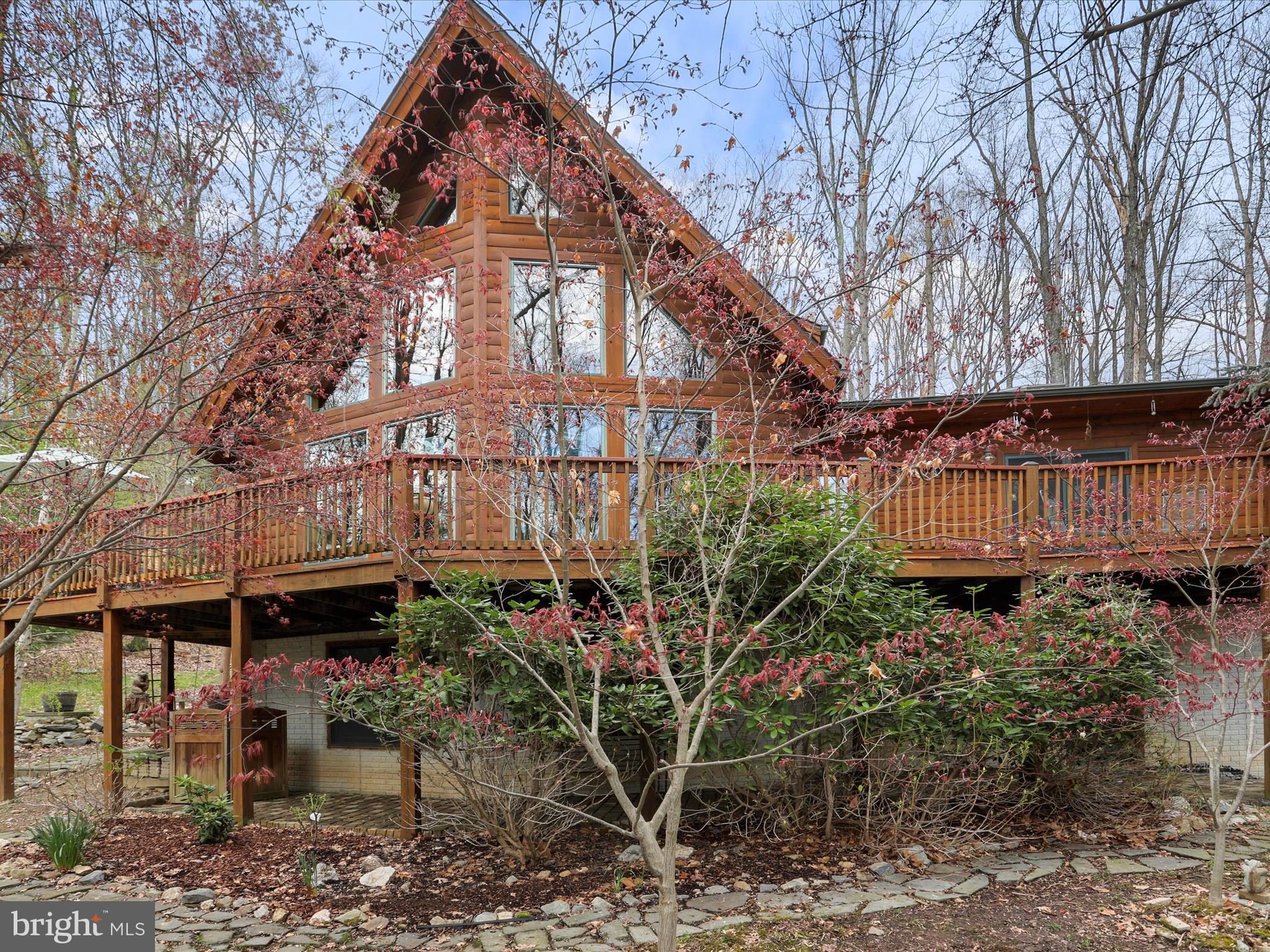 Don't miss this stunner! Make this bright and open chalet style log home nestled on 5 acres in Middletown your private oasis! Connect with nature every day in the majestic great room with gleaming hardwood floors, sharing a double sided, 2 story stone fireplace with the kitchen and dining space. The cathedral ceiling with exposed beams accentuates huge Andersen windows, bringing the outside in. The kitchen is appointed with light shaker style wood cabinets, warm slate look tile and contrasting granite countertops. Stainless Steel appliances, backsplash tile, a breakfast bar and ample table space complete this open area . Beyond the great room and behind the wrapping stairs to the upper and lower levels is the primary suite. With french doors to the expansive deck and a large, newly remodeled primary bath, this main floor primary suite is ready for a most relaxing night! Upstairs there is a large ensuite loft bedroom overlooking the gorgeous great room. The full unfinished walkout lower level provides additional space for rooms, and includes a woodstove great for cold winter nights. And a Generac whole house generator, as back up! All this plus an oversized 2 car garage, a covered porch, fenced yard, pavers below the deck, 2 propane tanks, new HVAC March 2024, new neutralizing system January 2023, new water heater January 2023. Come enjoy the lodge life!!
