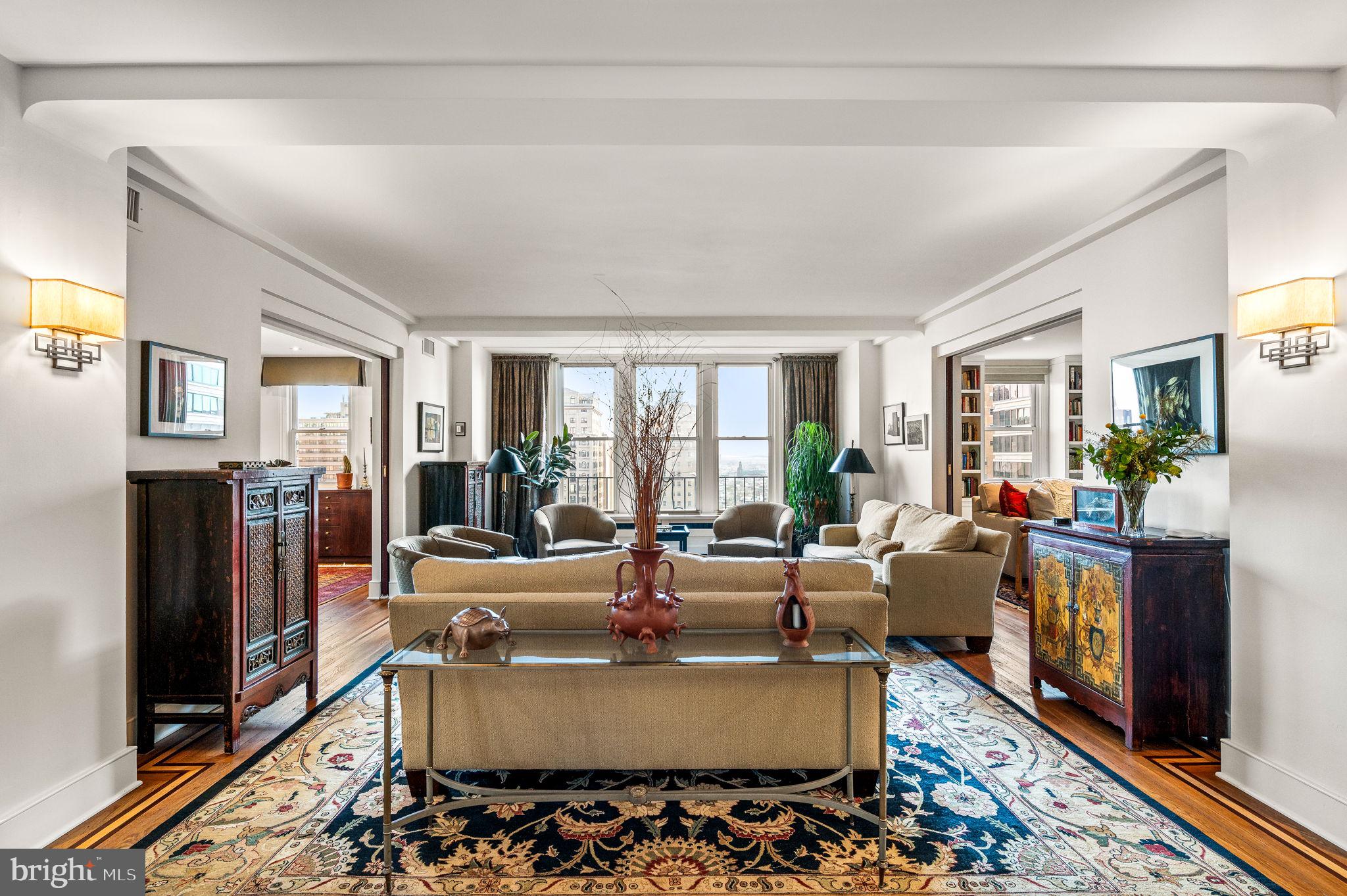 An exceptional offering at The Rittenhouse Plaza with over seventy feet of park frontage and thirteen windows overlooking Rittenhouse Square. This expansive corner three bedroom, three bathroom residence spans more than 2,400 square feet and enjoys three coveted exposures—east, south, and west, filling the interiors with natural light and capturing sweeping views of Rittenhouse Square, Walnut Street, and dramatic sunsets. The foyer opens into a spacious living and dining area with hardwood floors accented by mahogany inlay, creating an inviting setting for both everyday living and entertaining. The thoughtfully designed kitchen is highlighted by quartz countertops, a large center island with seating, vented gas cooking by Zephyr, extensive cabinetry, multiple pantries, and four large windows that bring in natural light and fresh air. The private primary suite offers a peaceful retreat with a sitting room or office, a customized walk-in closet, and a luxurious en-suite bath featuring a frameless glass shower, double vanities with medicine cabinets, private commode, a built-in linen closet, and a window. The second bedroom is versatile with a Murphy bed, two closets, custom built-ins, and an en-suite bath. The third bedroom, currently used as a den, is appointed with custom bookshelves, built-in cabinetry, recessed lighting, and a ceiling fan. The third full bath is finished with floor-to-ceiling tile, a walk-in shower with bench, and a frameless glass door. Additional features include a separate laundry room with a full-size LG washer and dryer, multiple walk-in closets, and three zones of efficient Bosch water-source heat pumps. The Rittenhouse Plaza is one of Philadelphia’s premier New York style pre-war cooperatives, offering 24 hour concierge service, a beautifully landscaped courtyard, and a pet friendly environment. The monthly co-op fee includes real estate taxes, Fios cable, internet, water, sewer, and building maintenance. A deeded parking space at the Wanamaker House is available for purchase. Perfectly located in the heart of Rittenhouse Square, this home provides a rare combination of space, views, and convenience with world-class dining, shopping, and cultural destinations just outside your door.