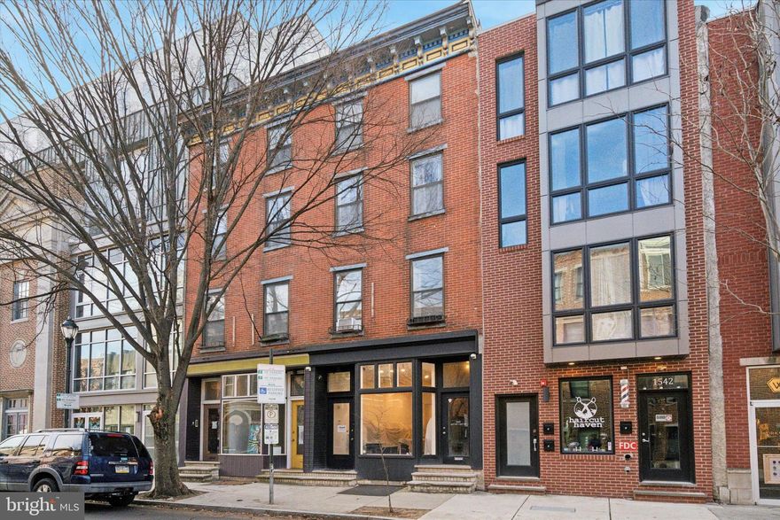 Rarely offered, this 4-story brick-front building includes more than 2,900 sq. ft. of above-ground living and commercial/retail space, situated on one of the most desirable blocks of South Street. 1540 South St. offers a store on the main/street level, a 1-bedroom apartment on the second floor, and a bi-level 2-bedroom apartment on the third and fourth floors. The second-floor apartment has its own private balcony at the rear, and the bi-level apartment features a private deck. The store and both apartments are equipped with central air conditioning. The entire property is occupied by long-term tenants.

Note that the store has a private entrance, separate from the apartments. Even better, the store boasts a large bay window, ideal for display on the high-traffic 15th block of South Street. The store also offers high ceilings, a private office area, a powder room, and a small backyard. The property has a full basement, accessible from both the store and the street through Bilco doors.

The second-floor 1-bedroom apartment is bright, boasts hardwood floors, and includes a private balcony at the rear. The top bi-level 2-bedroom apartment is modern, bright, and boasts a skylight, hardwood floors, and a large private deck. Note that the roof, where some mechanicals are located, can be accessed via a pull-down stair.

This unique property was custom rehabbed in the 1980s by an architect who ensured that every part of the property receives ample daylight. This feature is even felt in the main staircase, which accesses the apartments and charms with an exposed brick wall. Even better, the property offers a generous amount of storage space in each unit.

Own a one-of-a-kind 4-story building right next to the historic Royal Theatre, surrounded by numerous restaurants, shops, and everything that Rittenhouse Square, Graduate Hospital, and Broad Street have to offer. Learn more about 1540 South St. today.