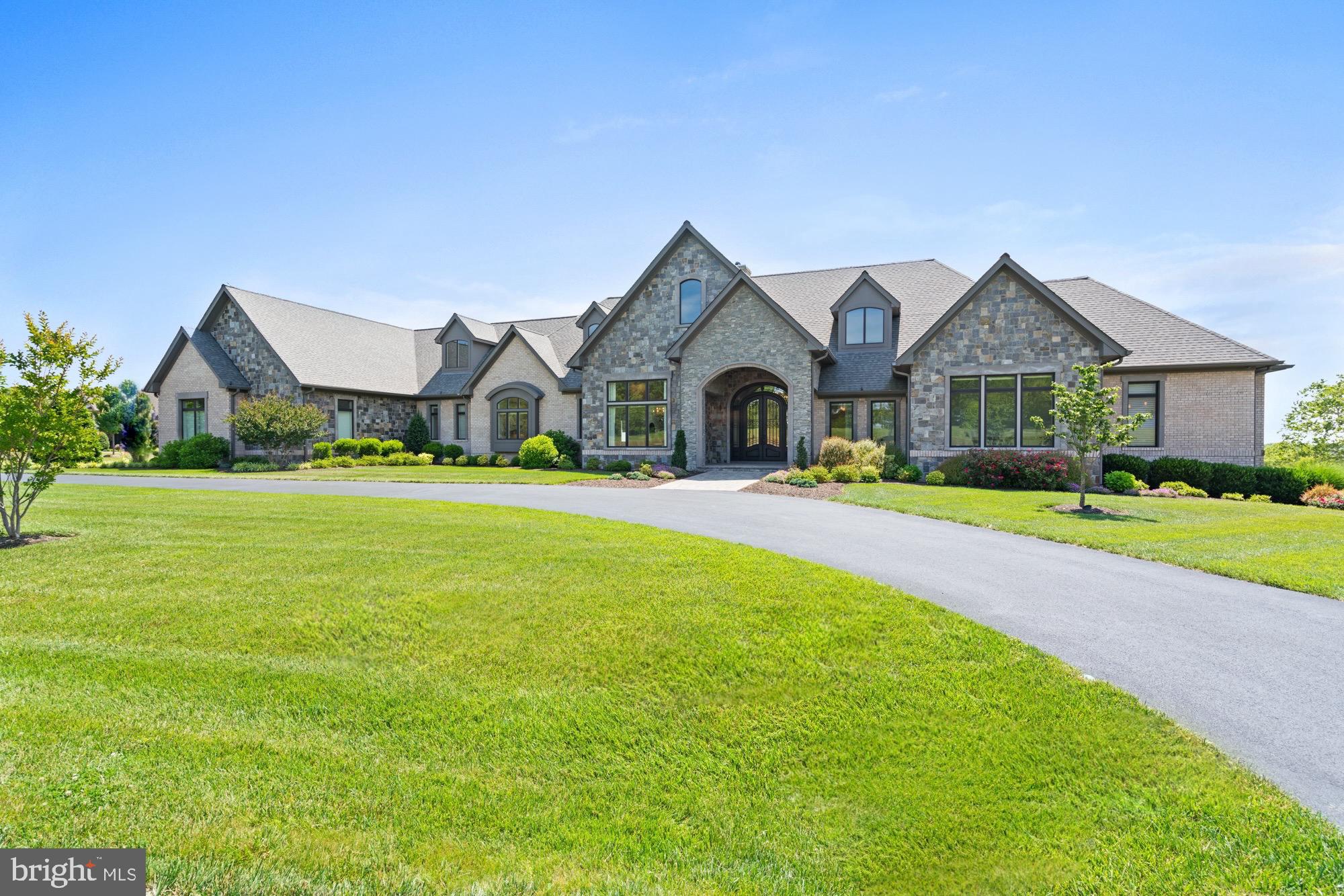 A one of a kind custom estate home available for the first time offering striking hilltop views of the bucolic countryside but close enough to the historic village of Warrenton you can walk to dinner. It’s a rare and enviable combination of town and country living but it’s the nearly brand new, 9,000 square foot, top of the line home that will leave you awe struck the moment you step through the iron front doors. You get one shot at a first impression and this one just about takes your breath away. An extraordinary grand foyer extends the full width of the house with approximately 15 foot ceilings. A sprawling open floor plan is highlighted by an oversized double height great room with a captivating DaVinci non heating fireplace that flows effortlessly to a large elevated stone terrace with views of the rear grounds, hillside and the historic Dakota barn. Floor to ceiling windows outfitted with motorized custom shades accomplishes the main strategy of bringing the natural world inside with an abundance of natural light. The eat in kitchen is thoughtfully designed with a timeless soft palate of neutral white colors including the quartz countertops and accented by a center island. It’s outfitted with every conceivable top of the the line kitchen appliance tailor made for the home chef including a six burner Wolf, double GE Monagram wall ovens, Sub Zero refrigerator, freezer and wine storage tower. The main level living area allows for large scale entertaining including a formal dining room and is serviced by a handsome wet bar with stemware cabinetry, refrigeration and ice maker. The screened porch is a multi season outdoor room for lounging, dining and viewing extraordinary sunrises. The main level primary bedroom suite is intended for two people who thrive in their own spaces. The bathroom features two vanities, oversized walk in shower with built in bench and elegant whirlpool tub. The primary dressing area includes two separate impeccable walk in closets with professional storage and hanging installations. The main level also features another generous ensuite bedroom, dedicated office and an additional bedroom or library. This is modern living at its best with the inclusion of an elevator, mud room, two powder rooms on each end of the first floor, full house generator, digital irrigation system and an insulated three car garage with a large bump out for a work space. The sophisticated light filled lower level with ten foot ceiling height is equally impressive highlighted by a stylish kitchenette, living area with a walk out to the rear grounds, two more bright ensuite bedrooms, gym and more than 1000 square feet of conditioned storage space. The home sits on just about two acres to ensure easy maintenance if you desire a turnkey retreat without the responsibility of larger land management. This is truly indoor and outdoor living at the highest level in the heart of Warrenton’s tranquil countryside but just 45 minutes from Dulles International Airport and less than an hour to the Washington, DC metropolitan area.