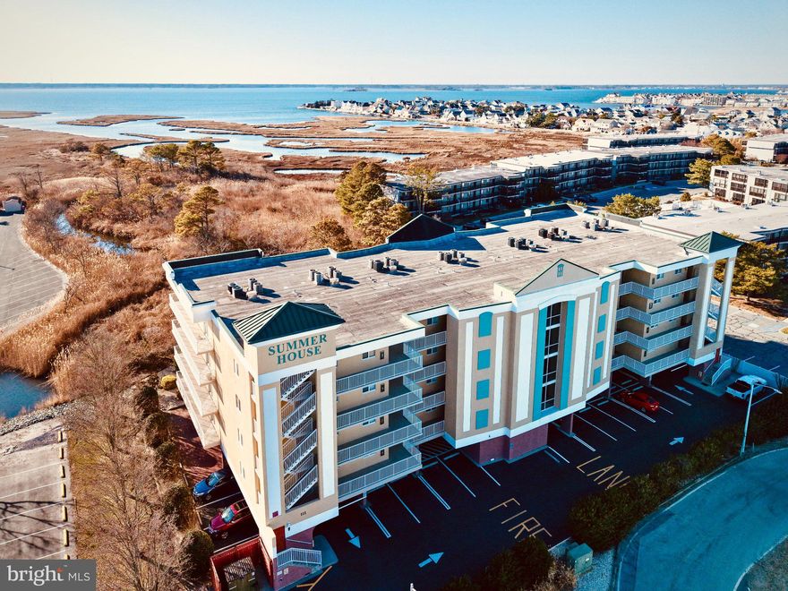 Welcome to Summer House, a well-appointed and secure condominium building in desirable North Ocean City, where coastal comfort meets relaxed seaside living. This beautifully maintained three-bedroom, two-bath residence offers a spacious, open layout, tasteful coastal finishes, in the heart of Ocean City. Inside, the home is finished in a neutral coastal color palette that enhances the abundant natural light and airy feel. High ceilings, crown molding, recessed lighting, and wide-plank luxury vinyl flooring can be found throughout the living spaces, creating an elevated beach aesthetic. The open-concept living area seamlessly blends the kitchen, dining, and family room, making the space perfect for both everyday living and relaxing. The family room features a cozy gas fireplace, perfect as endless summer days grow shorter, and a full wall of sliding glass doors that open to an oversized private balcony. From here, you can enjoy views of the community pool and glimpses of the bay, which become even more pronounced as the seasons change. The bright white kitchen is both stylish and functional, offering stainless steel appliances, a breakfast bar, generous cabinetry, and a pantry, all overlooking the dining and living areas. Just off the kitchen, a separate laundry room with a full-size washer and dryer adds everyday convenience. The primary suite is thoughtfully positioned for privacy away from the guest bedrooms. This spacious retreat includes a ceiling fan, walk-in closet, and a luxurious ensuite bath complete with a jetted soaking tub, separate stall shower, double vanity, linen closet, and private toilet room. Two additional guest bedrooms provide comfortable accommodation for family and friends and share a well-appointed hall bath. Summer House offers the ease of elevator access, and this unit includes two parking spaces, one of which is located in the covered under-building parking, as well as secure storge space for all of your beach gear! The residence is being sold furnished, making it move-in ready for immediate enjoyment. Residents and guests also enjoy access to the community pool, visible from the balcony, providing a relaxing spot to unwind after a day at the beach. Ideally located, Summer House places you just moments from the beach, iconic Ocean City attractions, popular nightlife, and an endless selection of outstanding dining and entertainment options. Whether you’re seeking a primary residence, vacation retreat, or investment opportunity, this inviting coastal condo offers the perfect blend of comfort, location, and beach life.