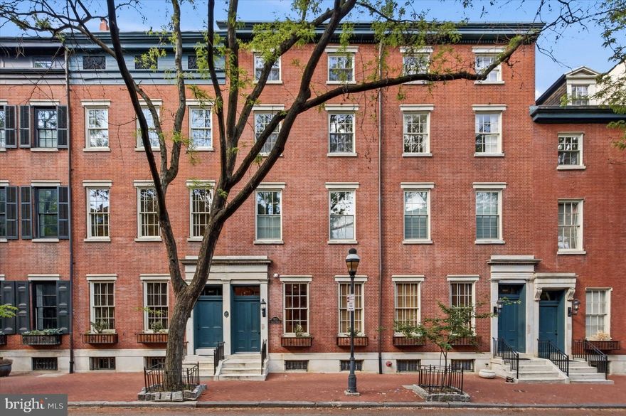 Nestled within the Coles House Condominium on picturesque, tree-lined Clinton Street, often affectionately referred to as “Midtown’s Delancey” for its timeless beauty, historic charm, and unmistakable sense of place, this exceptional 3-bedroom, 3.5-bath residence with parking offers the grandeur and architectural presence of a classic townhome, paired seamlessly with the ease and convenience of condominium living.
Framed by a stately red brick façade and elegant white marble steps, the building makes a memorable first impression. Inside, a well-appointed lobby with controlled entry sets the tone, while a rear entrance provides effortless access just steps from your deeded parking space. An elevator delivers you directly to the second floor, where Unit 203 begins to unfold.
A welcoming foyer with coat closet opens into a breathtaking living and dining space defined by soaring ceilings, rich hardwood floors, and a gas fireplace that anchors the room with warmth and character. Expansive south-facing windows flood the home with natural light, and with nearly all windows recently replaced, including six restored historic façade windows, the home now offers both enhanced efficiency and preserved architectural integrity. Fresh paint throughout provides a crisp, clean, move-in-ready canvas.
The open dining area sits at the heart of the home, perfectly scaled for lively dinner parties or intimate evenings alike. Just beyond, the thoughtfully designed chef’s kitchen features stainless steel appliances, custom wood cabinetry, generous storage, and a wraparound island that naturally becomes the gathering place, whether for morning coffee, a glass of wine, or conversation that lingers long after the meal is over. A conveniently located powder room completes this level.
A graceful staircase leads to two spacious secondary bedrooms, each with its own full bath and ample closet space, one currently styled as a flexible office or den. A dedicated laundry room with additional storage sits just off the hallway, adding everyday practicality to the home’s elegant design.
The entire third floor is reserved for a truly special retreat: a stunning primary suite that feels like its own private sanctuary. Here, a generously sized bedroom with soaring ceilings overlooks acclaimed Clinton Street and is complemented by abundant closet space and a luxurious bath featuring a walk-in shower, soaking tub, and large marble double vanity. An additional staircase leads to attic storage, an uncommon and highly valuable bonus in city living.
Back on the main level of the building, residents enjoy a mail and package room, bicycle storage, basement storage, and easy rear access to parking. The association is known for its attentive stewardship and proactive maintenance, providing confidence in both the building’s care and its long-term value.
All of this, set on one of the city’s most enchanting blocks, where mature trees canopy the street, historic façades create a storybook backdrop, and the rhythm of neighborhood life feels both peaceful and connected. With a Walk Score of nearly 100, the very best of Center City living is just moments away.
A spectacular home. A storied street. And a setting that feels nothing short of magical.