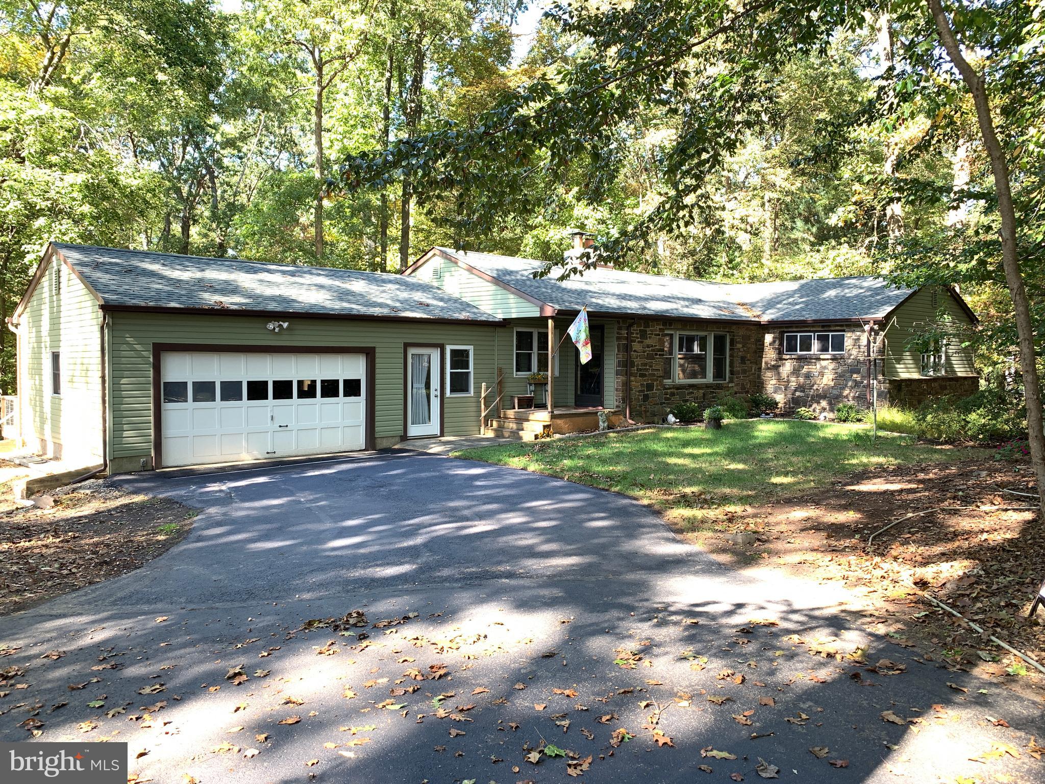 WOW...GREAT NEW PRICE and this  one is definitely not a drive-by!  Home is deceiving from the outside and definitely worth a visit.  PLEASE NOTE...PUBLIC RECORD IS NOT CORRECT...HOME DOES HAVE PUBLIC SEWER!  Location location location in beautiful BUCKINGHAM TOWNSHIP and the highly rated CENTRAL BUCKS SCHOOL DISTRICT.  Sunnyside Drive is a quiet and friendly street. Neighbors enjoy strolling along through the community that is surrounded by numerous large and majestic properties, all with easy access to York Rd (Rt 263), close to the intersection of Rt 263 and Rt 313 and just minutes from the 202 Bypass.  This updated rancher has a great open floor plan offering a spacious living room, dining room and kitchen combination! Newly refinished, gleaming hardwood floors greet you as you enter and travel throughout the home. It sits on a very private, and deep, 1.55 acre lot.  If you enjoy the rural beauty, and privacy, of mature trees, yet want to be close to everything, this is the perfect lot for you.  In 2017, the kitchen/dining room area was totally remodeled; walls were opened to accommodate a more open floor plan which flows right into the living room. Beautiful stone fireplace and large windows accent the living room. A design perfect for entertaining! Most of the rooms have been recently repainted. Four good sized bedrooms, each have new, lighted ceiling fans. The paneled room right off the kitchen could also be used as a more formal dining room, computer room or study.  Bathrooms have been updated, new vanity, new pedestal sink, new toilets, new medicine cabinets and fixtures. Tile walls, tub and floors have been beautifully re-glazed to provide a more contemporary look. Master bedroom has its own bath. The fully enclosed, and heated, breezeway between the garage and kitchen area has been transformed into an area for laundry or just a perfect, cozy nook for a good book and your favorite brew. The breezeway room has been freshly painted and the new lighted, ceiling fan makes it bright and comfortable; a perfect get-away retreat. The huge basement (49x26) has so much potential. Just bring your ideas and make it your own! Rough plumbing is there, should you decide to install a basement bathroom. There is also an additional storage room (9x13) in basement area. Driveway has been coated and a new exterior drain was installed along the length of the two-car garage in September 2019. New roof, siding and gutters were installed in 2017. New oil tank and heater just installed October 2019. Deck needs work but offers wonderful views of the park-like setting of YOUR beautiful and secluded 1.5 acre wooded lot. Schedule your showing today!