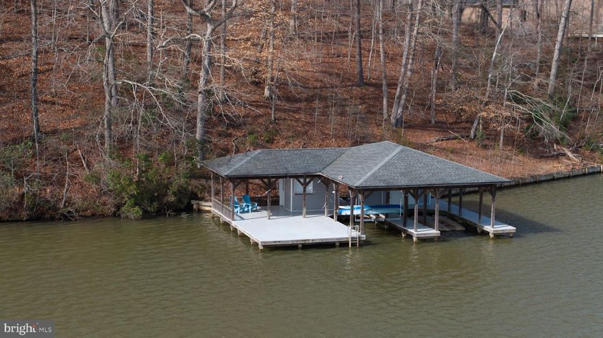 Discover an extraordinary opportunity to own a deep-water waterfront lot in one of Lake Anna’s most coveted midlake locations on the public side, offering seamless access to all marinas, restaurants, and attractions. This rare find features 220 feet of mostly bulkheaded shoreline, ensuring stability and longevity for your dream lakeside retreat. You can build that retreat with peace of mind, as this property has a soil feasibility letter, site plan, and is suitable for a four-bedroom home.
A true lake lover’s dream, the property comes with an expansive, existing boathouse—a rarity in today’s market! Thoughtfully designed for both recreation and functionality, this composite-decked structure includes two boat slips (11’x26’ and 10’x24’), one equipped with an electric lift for effortless lake access. Enjoy breathtaking panoramic views from the spacious 20’x20’ sundeck, or entertain guests at the 9’x8’ tiki bar with a roll-up door, creating the ultimate waterfront oasis. Additional secure storage space ensures all your lake gear is within reach. 
With a pre-installed driveway and path to the water, this stunning lot is easy to access and view, making it the perfect canvas for your dream home or vacation getaway. Deep water frontage guarantees prime boating, swimming, and fishing right from your doorstep. Conveniently located near shopping, dining, and everything Lake Anna has to offer, this property provides the perfect blend of tranquility and accessibility.