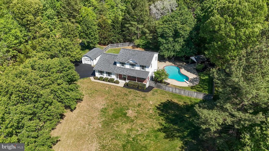 Situated in a quiet cul-de-sac on just over 3 acres, this well-maintained home truly embodies “location, location, location.” Come fall in love with the pride of ownership evident the moment you pull up to a gorgeous tree lined driveway. Come have a seat and enjoy relaxing on the front porch while watching Mother Nature. Inside you will appreciate the hardwood flooring and the remodeled kitchen, featuring beautiful 42 inch maple cabinets, stainless steel appliances, a stunning backsplash, and granite countertops, ideal for cooking and entertaining—imagine sharing the space with a Top Chef, complete with an eat-in area. You will be sun-kissed in every room with the amount of natural lighting shining through. A versatile first-floor layout includes a dining room/first-floor bedroom with a private full bathroom, also a welcoming family room with a pellet stove, steps away onto an upgraded deck with composite decking and an awning. Practical updates include a 2016 hot water heater, a 2025 garage door, a 2018 roof, and both HVAC units replaced in 2012 and 2014,  plus a generator for peace of mind and so much more. Upstairs hosts an owner’s suite and two generously sized secondary bedrooms with modernized finishes. The basement offers expansive flex space and a built-in bar, just steps from a gorgeous pool with a new cover, pump and extensive hardscape for sunny-day entertaining, plus ample secure storage with two sheds. NO HOA which means bring your RV's, boats and trailers. Easy commuter routes to all local Military bases.
