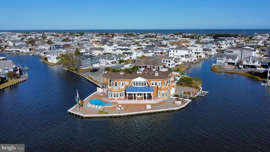 Luxury waterfront home on the largest bayfront parcel in the town of Fenwick Island.  This exquisitely designed, custom-built home with a pool sits on a half-acre peninsula with nearly 400 feet of waterfront, and is just a short, easy walk to the beach. Carefully crafted with the highest level of quality and attention to detail, this remarkable property was architecturally designed to capture stunning water views from every room. Elegantly appointed with high-end furnishings and finishes, this spacious residence boasts over 6,500 square feet of living space, featuring geothermal HVAC, six generously sized bedrooms, five full luxury bathrooms, and a powder room. Step through the front door into the expansive great room, where walls of windows showcase breathtaking bay views with bright southern exposure. The meticulously crafted coffered ceilings further highlight the superior craftsmanship that went into designing this exceptional home. Multiple sets of full glass Anderson double doors line the bayfront, opening onto an expansive covered lanai with dual remote controlled Varisol Awnings with solar drop screens and a waterfront hardscaped patio, complete with a heated saltwater pool. Inside, the gourmet chef’s kitchen is equipped with high-end appliances, including an eight-burner gas range, multiple sinks, and dual dishwashers, making entertaining effortless. The eat-in kitchen is conveniently positioned just off the living room, with easy access to the formal dining room, which offers equally impressive views of the open bay and adjacent corner canal. Also on the main level is one of two primary bedrooms, along with an oversized laundry room and a powder room.  Upstairs, there is a second family room, complete with a wet bar and gas fireplace as well as a second primary suite with a private bayfront balcony.  Four additional bedrooms and three full bathrooms complete this level.  The oversized three-car garage includes a huge storage area above.  This home also features a private boat slip with an electronic lift and two smaller lifts accommodating up to four jet skis. The bulkhead was upgraded in 2024 and the exterior has been enhanced with lush landscaping, irrigation and custom lighting. Additional features include an audio/visual system that was upgraded in 2023, central vacuum system.   Situated on a half-acre parcel, this exceptional bayfront retreat was built to meet CAT 3 hurricane standards and was featured in both Coastal Style Magazine and on The Beach to Bay Cottage Tour.  Offering the perfect balance of privacy and convenience, this incredible home is just a short bike ride to exceptional restaurants and boutique shops of Fenwick Island, yet is tucked away at the end of a quiet, non-thru street within the town limits.