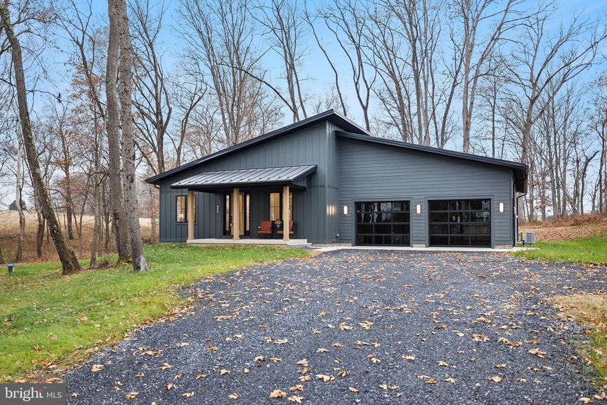 Welcome to 126 Chickadee Court, a combination of rustic character with modern comfort makes up this contemporary barndominium-style home. Featuring a striking dark Iron Gray Hardie-plank exterior, metal roofing, lean architectural lines and warm wood accents.

A covered front porch welcomes you into a dramatic entryway with 11-foot ceilings, where the interior's elements harmonize with the structural integrity of the 2x6 framing giving enhanced energy efficiency and aesthetics.  The expansive open concept main floor of 2,016 sq ft of living area flows straight from the foyer to the rear covered porch, creating a seamless transition between indoor and outdoor living.

The great room boasts high beamed ceilings with Andersen French doors and windows providing year-round enjoyment of the surrounding mature woodlands and nature views.  A linear fireplace sets the mood for unwinding in the evenings to social gatherings with family and friends.  This area flows into the dining space and kitchen, making it ideal for entertaining and everyday life.  The centerpiece of the kitchen is a large island with a farm sink and abundant quartz counter space for cooking and hosting complete with high-end appliances.  Merillat Masterpiece cabinetry features soft maple in a beautiful barley tone and clean white finishes including a servery area with glass doors for showcasing your favorite collections. 

Conveniently located off the foyer is a spacious and light infused office space.  Across the hall is the second bedroom, positioned conveniently to the hall bathroom with tiled tub/shower.

The primary suite features 11-foot ceiling, private French door access to the back porch, a generous bathroom with dual vanities, expansive tiled shower, and a large walk-in closet.

Access to the garage is through the Mudroom area, with built-in bench seating, storage cubbies, cabinetry and quartz counterspace for ease of organizing.  

The drive through garage is equipped with three overhead doors all with tinted, insulated glass allowing natural light to infuse the 1,450 sq ft garage space. Whether it's used for a collection of classic cars, sports/adventure hobbies or workshop space for family projects, the garage's ample area caters to many needs. Conveniently pre-wired for 220 plugs.  Taking care of the Pets needs can be conveniently handled at the dedicated built-in stainless steel dog washing station. 

A full 2,016 sq ft unfinished basement with a walk-out access to an English Patio through French doors and windows is ideal for a family/game room or in-law suite. The space features roomy 8 ½’ ceilings and stub-in for a full bath.

A total of 4.521 acres including mature woods, open pasture land, a pond is suitable for an array of hobbies from horse, livestock, gardening, sports, art and nature enthusiast alike.

Tucked off a quiet cul-de-sac street in the 4 lot Walton Woods Subdivision, this home is minutes to Woodstock, offering easy accessibility to shopping, hospital, and restaurants. Convenient 30-minute commute to Winchester or Harrisonburg and 90 minutes to Northern Virginia.