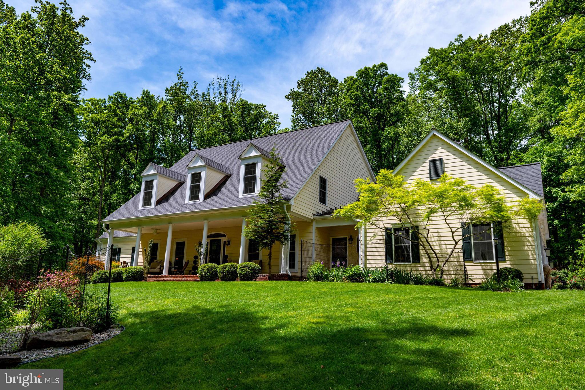 Nestled on a beautifully landscaped and gated 3.5-acre lot framed by a classic paddock fence, this exceptional 4-bedroom, 5.5-bath Southern Living style home offers the perfect blend of luxury, comfort, and natural beauty. Inside, you'll find rich cherry and oak wood floors, elegant crown molding, chair rail accents, and a striking curved staircase. The spacious kitchen features a large island, stainless steel appliances, and a double oven, flowing seamlessly into a sunroom with skylights and a formal dining room. The generous living room and den provide inviting spaces for relaxation. The main-level primary suite is a private haven, complete with gas fireplace, a sitting area surrounded by windows, spa shower, dual vanities, and a walk-in closet. Three additional bedrooms upstairs each include their own attached bath. The finished basement offers French doors which open to a lower patio, a full bath, a large crawlspace, and ample storage areas.
Outdoors, enjoy a truly scenic setting with a view of towering trees that create a peaceful, private backdrop. A large patio with a full masonry fireplace anchors the expansive outdoor living space, ideal for entertaining or unwinding. The property also features a greenhouse with a small vineyard, 3-car garage, storage shed, and a giant side yard garden, perfect for cultivating your own produce and flowers. Efficient living is enhanced by a tankless hot water heater, making this home as functional as it is beautiful. All house systems have been updated within the last 10 years, so maintenance is minimal.