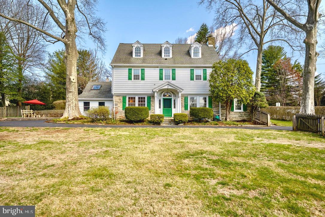 Welcome to 112 Banbury Way — A Classic Wayne Colonial Just Steps from Town. Nestled in the heart of downtown Wayne, this timeless 1920s three-story Center Hall Colonial perfectly blends historic charm with thoughtful modern updates. Located on one of Wayne’s most beloved streets, this home offers a rare opportunity to enjoy the walk to Wayne lifestyle in the top-rated Radnor School District. From the moment you arrive, you’ll be captivated by the architectural details that make this home special. Leaded glass windows frame the stately front entrance, and a covered flagstone porch welcomes you with classic curb appeal. Inside, original hardwood floors run throughout all three levels, maintaining the home’s warm, authentic feel. Step into the true Center Hall layout, where the home opens graciously in three directions — to the Living Room on the left, Dining Room on the right, and straight back into the Kitchen and vaulted Family Room. The Living Room is bright and inviting, with a wood-burning fireplace, beautiful custom surround, and built-in bookcases. A sun-drenched office—accessed directly from the Living Room—features windows on three sides, an exterior entrance, and makes for the perfect work-from-home space. Across the hall, the formal Dining Room glows with natural light and is accented by four elegant sconces, offering the perfect setting for dinner parties or family gatherings. The updated Kitchen offers excellent workspace, light custom cabinetry, new double ovens and dishwasher, a breakfast bar, and views into the dramatic vaulted Family Room. With exposed stone walls and a cozy wood stove, this is a space that brings friends and family together for good times and lasting memeries. A large Mudroom with cubbies, flagstone floors, and access to the backyard adds everyday convenience, along with a well-placed Powder Room. Upstairs, the second floor offers three comfortable bedrooms and two full baths, including a spacious Primary Suite with a large walk-in closet (featuring a built-in ironing station) and an updated en-suite bath with custom tile work and double vanity. A second full bath, a convenient laundry closet, and two additional bedrooms complete the level. The open staircase continues to the third floor, where you’ll find two more charming bedrooms and a full bath — each space rich with architectural details and filled with natural light. The backyard is a private, level oasis, fully enclosed by mature plantings, fencing, and stone walls. A circular patio, cozy tree house, and a secluded garden area make it ideal for entertaining, relaxing, or imaginative play. Located just steps from everything downtown Wayne has to offer — restaurants, coffee shops, boutiques, the Wayne train station, and more — this is Main Line living at its finest.