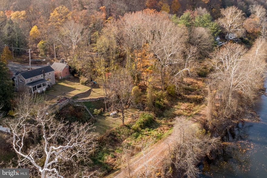 Waterfront property not in the flood zone! Nestled in the bucolic village of Lumberville sits a charming home with commanding views of the Delaware River. Once owned by three generations of Italian stone artisans, this one-of-a kind property with its unique architectural elements and stylish aesthetic, will simply captivate you. Iron fencing with stone posts and an inviting portico lead to the front entrance. As you enter, an exquisite stone fireplace with its intricate carved details including opposing griffins and floral embellishments, takes center stage. Beautiful wood floors lead to the open living space with paneled walls and an expansive picture window showcasing stunning river views. Another wood-burning stone fireplace, thoughtfully designed and executed with symmetry and precision, takes its prominent position in the living room. The dining area is open to the living space and leads to the kitchen. An unexpected nook for collectibles, silver and glassware is a sweet surprise. The kitchen has a vintage vibe, and features a stainless-steel double basin countertop sink, wood block and tile counters, open shelving and breakfast room. The upper level includes a primary bedroom with vaulted ceiling, walk-in closet, wood floors, deep window sills and an antique cabinet for linen storage. The primary bathroom is new and has a stall shower, subway tile and linen storage. Two more spacious bedrooms and one hall bath complete the second floor. In the basement you will find multiple rooms with options for a wine cellar, workshop, additional storage and laundry. Upgraded utilities include a Bosch Propane multi-zone heating system, and two Bryant AC systems (in basement and attic). Step out the back for panoramic water views and a front row seat to natural wonders each day. The spacious covered porch is the ideal spot for outdoor dining and entertaining. Complete with stone flooring and bluestone surround, the porch leads to the rear yard where you will pass a stone-carved sink, one of the many unique signature statements of the former property owner’s creative legacy. The lower terrace affectionately called “the ruin” creates a stunning perch upon which to soak in the expansive river view. The additional structure on the south-end is certain to capture your imagination. With its tempting river view from a Juliet balcony, brick walls and solid wood floors, this stand-alone structure has potential for a studio or office. One floor beneath is the former stone carving workshop with a fireplace and access to the rear yard. The two car garage on the north-end has two deep stalls and room for storage on the first level. For the outdoor enthusiast, the upper level offers additional storage capacity for recreational equipment, accessories and river toys. You will love the close proximity to the Delaware Canal towpath, local culture, first class dining and the Lumberville general store! This home is a testament to the artisan’s quality craftsmanship and impressive signature style. Before long, you could be the next steward of this intriguing property and own a rare piece of Lumberville history!