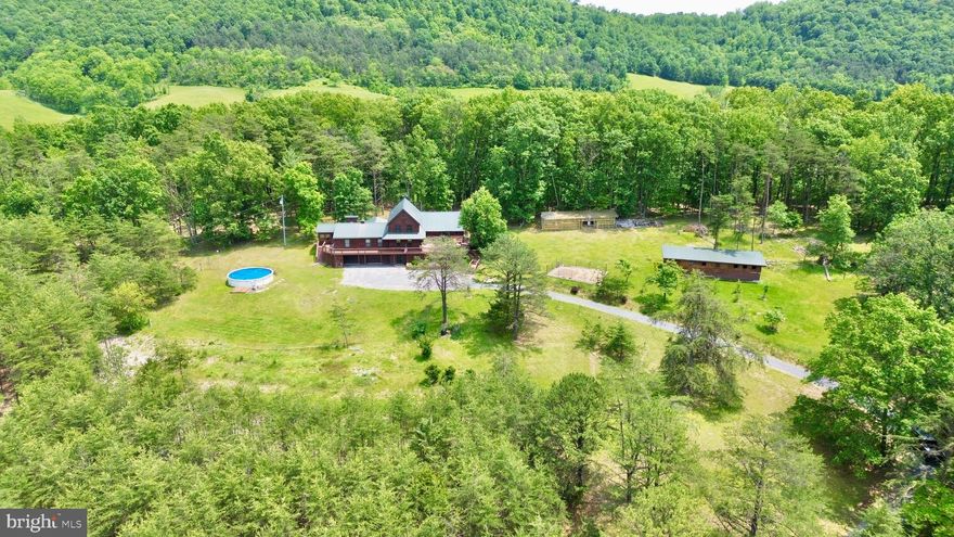 Beautiful custom-built cedar home with stunning views! Enjoy mountain living at its best in this spacious home on over 8 private acres. The main floor features a welcoming Great Room with an impressive natural stone fireplace and cathedral ceilings, a dining room, and a kitchen—with a breakfast bar, stainless steel appliances, and granite countertops—plus French doors leading to the family room. The master suite includes a propane fireplace and access to a private three-season porch. An extra bedroom, half bath, and another three-season sunroom add to the home's versatility. Upstairs, you'll find a second master suite, an additional full bathroom, and a charming loft overlooking the Great Room's stone fireplace. The walk-up, partially finished attic offers additional storage or expansion opportunities, while the walk-out basement with a large integral two-car garage, workshop, laundry area, and storage space enhances functionality. Step outside to enjoy the wraparound deck that showcases the picturesque views and is perfect for gatherings and outdoor living. The property features an outdoor stone BBQ area, an above-ground pool for summer fun, an approximately 15x40-foot barn with a cement floor and three small animal stalls, a large 8x40-foot enclosed woodshed, over 20 assorted fruit and nut trees, and ample open areas for gardening and recreation. Hunt on your own land or in multiple nearby PA and MD State Lands, plus enjoy nearby fishing in both Flintstone and Town Creek. Close to I-68, this home is located just 10 minutes from Rocky Gap Casino, Resort & Golf, as well as Buchanan State Forest and the PA Mid-State Trail. It provides an ideal escape to nature with easy access to amenities and outdoor adventures.