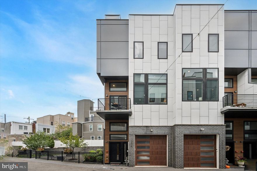 Experience the best of luxury urban living in this stunning 3-bedroom, 3.5-bathroom townhome with a two-car garage located in the highly sought-after gated community of Graduate Square. Enjoy just under 4 years remaining on the tax abatement, offering exceptional long-term value. This home is one of a handful of end-unit homes. A twin. Only attached on one side. This gives the owner an added exposure to all the western light one could wish for. The home’s spacious two-car garage design accommodates a 2-car vehicle lift, allowing for easy parking of two full-sized vehicles — a true rarity in the city. The fully finished basement provides flexible space ideal for a home office, gym, media room, or even a fourth bedroom.
The first floor welcomes you with a gracious foyer, coat closet, and a versatile office area that opens through sliding glass doors to a peaceful private patio. This level also features a large bedroom overlooking the patio and a full bathroom — perfect for guests or multi-generational living. Upstairs, the main living area impresses with soaring 12-foot ceilings and an abundance of southern light pouring through floor-to-ceiling windows fitted with custom blinds. The open-concept design seamlessly connects the living, dining, and kitchen areas, creating an ideal environment for both entertaining and everyday living. The chef’s kitchen features sleek quartz countertops, a spacious island for casual dining, and high-end GE Profile stainless steel appliances. Step out onto the balcony from the living area to enjoy your morning coffee or an evening breeze. The third floor features a bright secondary bedroom with a walk-in closet and access to a full bathroom located in the hallway. A laundry closet equipped with a full-sized washer and dryer, along with a utility sink, adds convenience. The primary suite offers stunning views of the Center City skyline, a generous walk-in closet, and a spa-like bath complete with dual vanities and a luxurious rain shower. Continue to the expansive roof deck, a private urban retreat with custom planters, lounge seating, and breathtaking panoramic city views—perfect for relaxing or entertaining.
Graduate Square residents enjoy a low HOA fee that covers trash removal, landscaping, and snow service, as well as access to a beautifully landscaped private park. The pet-friendly community boasts an impressive Walk Score of 85, indicating that most errands can be easily accomplished on foot. Just steps away are local favorites like Grace Tavern, Illata Restaurant, Igloo Frozen Yogurt, Dock Street Brewery, and Sidecar Bar & Grill, as well as grocery options including The Fresh Grocer and Heirloom Market. Fitness and wellness are conveniently accessible with City Fitness, Tuck Barre & Yoga, Stretch Zone, and more nearby. Conveniently located near CHOP, UPenn, Drexel, and the Schuylkill River Trail, with easy access to I-76, South Street Bridge, and Philadelphia International Airport.
Graduate Square offers luxury, location, and lifestyle — all in one exceptional home.