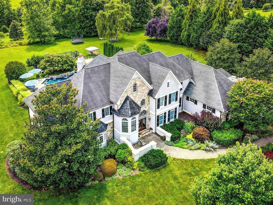 Situated within the desirable neighborhood of Cloverland, this gorgeous French country style home welcomes you as a place of respite and serenity.  Winner of the Home Builders Association "Home of the Year",  sitting on just under 7 acres and backing to 50 acres of preserved land, enjoy all that nature has to offer with a stream running along the edge of the property, mature fruit trees sprouting with figs, cherries, and more, and raised garden beds with bountiful harvests.  This retreat boasts 6 bedrooms, 4 full and 2 half bathrooms, center two-story foyer, custom millwork, two fireplaces, formal study with coffered ceilings and built-in bookshelves, and a mudroom with custom lockers, just to begin.  On the upper level, the impressive primary suite is complete with a gas fireplace, sitting room, dual walk-in closets, back entrance, and tranquil ensuite.  Separate vanities, soaking tub, water closet, walk-in shower with rainfall shower head and a thoughtful glass window opening to heated towel racks for great convenience, await in the ensuite.  Remainder of the upper level consists of two separate wings, each with two bedrooms and a full bathroom.  Furthest bedroom currently serves as a quaint library, just next to the laundry room.  You’ll find the heart of the home in your spacious kitchen, overflowing with natural light, oversized island with seating, walk-in pantry, beverage fridge, prep sink, sitting area, as well as a breakfast nook which overlooks both your living room fireplace and your resort style yard.  Step out onto your rear deck and down the steps to relax in your spa tub, soaking in views of the in-ground heated pool, its fountains, pool house, and greenery providing the utmost privacy.  Acreage stretches beyond a wooden playground to a field that would allow for an additional outbuilding or make a perfect grazing pasture, just awaiting a horse or two.  Should you need space for an au pair or in-law suite, they would find their own private entrance on the rear of the home through French doors into the walkout lower level.  This space includes a sun-filled bedroom (with additional rough-in next-door for a potential 5th full bath) and kitchenette, just down the hall from a full bathroom.  Movie buffs alike will appreciate the home theater area with a motorized projector, built-in speakers, and starlight ceiling.  This beautiful, multifunctional open floor plan design was featured in Houzz home design and is perfectly integrated with the whole house Crestron automation system.  Additional amenities include home gym, ample storage space, three-car garage with GarageTek storage system, widened parking area on driveway, copper gutter system, and partial generator.  Impeccable abode just waiting to impress in person.