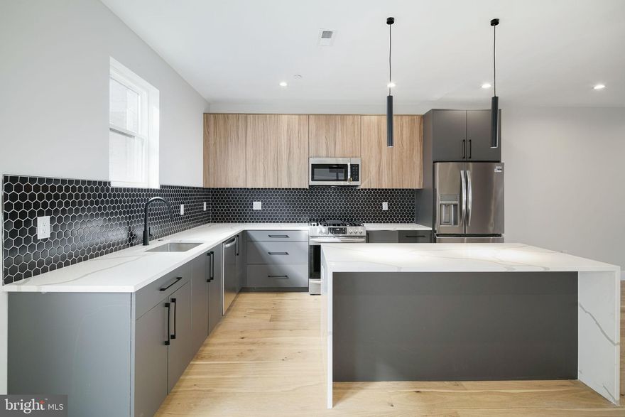 BUILDER INCENTIVE - Builder offering $10,000 credit towards closing costs! Brilliant and modern. Tilton Head Row stands a 16-home community, encompassing 14 luxury townhomes and 2 entirely unique carriage houses. Devised with sophistication, superb finishes, garage parking and the exhilaration of living in what Forbes calls, “America’s Hottest New Neighborhood”.  You will truly marvel as you walk up to this unique 24' wide carriage house. Inside you will find a foyer area, perfect for parking a bike or even a Vespa.  Take a few flights up to the main level, explore the open concept floorplan with custom iron railings and stunning wide plank white oak hardwood flooring throughout. This massive living area is undeniably an ideal entertainment space. Find the dining area sitting between the living room and the immaculate gourmet kitchen. The kitchen is truly remarkable, featuring 2-tone, dark grey and woodgrain 42" cabinets w/ under cabinet lighting, Frigidaire Gallery®  stainless steel appliance package including a 5-burner stove with griddle, Calcutta quartz countertops and black hexagon mosaic tile. All accented with matte black hardware. An oversized island sits at the center of the kitchen with a dual waterfall edge and sleek hanging pendants overhead.  Walk out to balcony set off the kitchen overlooking the rear of the property to enjoy a warm expresso in the morning. The remainder of the main level features the powder room.   A laundry room sits at the top of the stairs as you make your way to the bedroom level. Next you will find two spacious bedrooms, each with an en-suite bath. The street facing bedroom holds large bay windows. The bath is adorned with beautiful tile, most notably the PORCELENOSA textured wall tile in the tube shower. A free floating European vanity and matte black plumbing fixtures truly imbue the space. The grandiose primary bedroom holds extra closet space and an absolutely immaculate "spa like" primary bathroom.  You will find a free-floating double vanity, frameless LED light vanity mirror and a lavish walk-in shower, laden floor-to-ceiling in PORCELENOSA textured wall tile.  Rinse from every angle as you utilize the dual wall, hand head and raindrop shower heads. It boggles the mind to think of all you can do in such a shower. The carriage house features one of the largest roof decks you will ever see and it wouldn't be complete without immaculate unobstructed views of skyline.  The views of both the skyline and the Benjamin Franklin bridge are nothing short of spectacular from Tilton Head Row. Other features include all LED recessed lighting, matte black door hardware w/ level handles, Delta® bathroom plumbing fixtures. Ring video doorbell, Bluetooth®  actuated sound system, Carrier HVAC system and much more. Conveniently located close to I-95, Tilton Head Row is located just a stone's throw away from popular Fishtown hotspots such as Suraya, Frankford Hall, La Colombe, Punch Line Philly, The Filmore and Rivers Casino. 10-year tax abatement and builder warranty included. Schedule a private tour today to secure a home at Tilton Head Row.