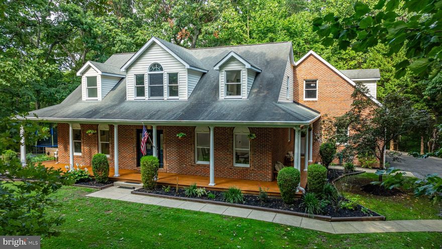 Welcome to this stunning all-brick Cape Cod home, set on a sprawling and private 3.88-acre lot, perfect for those seeking luxury and seclusion. The exterior has been freshly power washed, highlighting the refined wraparound front porch with decorative columns and refinished hardwood floors. The property is fully fenced, ideal for pets, and features a new gate at the driveway. Step inside to find hardwood floors throughout the main level, a decorative front door with etched glass sidelights, and a formal dining room adorned with a dramatic tray ceiling, recessed lights, and a decorative chandelier. The spacious and dramatic two-story family room boasts a vaulted ceiling, skylights, a transom window, and a floor-to-ceiling stone fireplace with a woodstove insert, complemented by an oak mantle and an alcove entertainment center. The abundance of windows and natural light is enhanced by a balcony overlooking the family room, complete with two ceiling fans. The renovated kitchen is a chef's dream, featuring 42-inch cabinets, a mobile center island, stainless steel appliances, granite countertops, a designer tile backsplash, LED recessed lighting, and a pantry. Adjacent is a side door entrance to the laundry room, equipped with a front-load washer and dryer. The main-level owner's suite offers new hardwood floors, his-and-her closets (with a walk-in and closet organizer), a ceiling fan, and double doors leading to the backyard. The ensuite bathroom has been renovated with an oversized soaking tub, dual sink vanity, step-in shower with designer glass doors, oversized marble tile floors, modern light fixtures, and a private toilet area. A unique spiral staircase with a hardwood finish and metal railing leads to a private office area, featuring a ceiling fan, carpeting, numerous windows for natural light, and a new glass door. This office also connects to a large 25 x 12 storage area over the garage. The oversized two-car garage includes dual garage door openers, a workshop area, fixed stairs to a floored attic, and a back door to a screened-in porch. The upper level houses a large bedroom with a fully renovated bathroom, a catwalk overlooking the family room, a second bedroom with a cathedral ceiling, recessed lights, a ceiling fan, and three windows with a half-round design, as well as a third bedroom. The renovated hall bathroom features marble tile floors, a tub and shower combo, a new vanity, mirror, light fixture, and toilet. The home is equipped with a dual zone heating system; the upper level utilizes a 2019 all-electric heat pump, while the lower level has an electric heat pump with propane backup. A propane hot water heater ensures efficient hot water supply. The basement is a true retreat, featuring a finished man cave with a wet bar, sink, refrigerator, and LVP flooring. Additionally, the partially finished walkout basement includes flooring, drywall, a workshop area with a built-in bench, extra electrical outlets, and a pegboard wall. High-speed internet ensures you stay connected, making this home the perfect blend of comfort, luxury, and modern convenience.