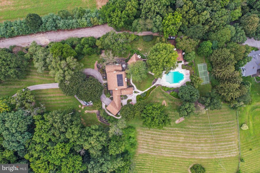 If you value privacy, exquisite views and a resort lifestyle, then look no further as this regal estate, high on the hill is sure to please!  With attention to every detail, this property presents an unmatched level of impeccable design. Enter through a gorgeous masonry pillared gate and be impressed by the tree-lined entryway as you are greeted with breathtaking views that go on for miles. Luxury exudes all around you on this 10+ acre, resort-style residence. An expansive renovation of the entire property showcases this one-of-a-kind custom property for one with distinguished taste. Enter through the double doors to the grand two-story foyer featuring two closets and a settee. Go upstairs and discover two bedrooms complete with walk-in closets and a full bath or continue on the first floor to the massive main living room area with exposed wood beams, a fireplace with beautiful stonework and even a wet bar to service this room. Follow the French doors to the dining room and discover the wall of windows with the extensive, scenic views on full display. Here you will also find a multi-level outdoor terrace, with landscaping to complement the round paved terrace leading to the pool.  Also in the dining room is a bar pass-thru and plenty of room to entertain noted by the oversized dining room table. The kitchen boasts beauty and grandeur that any chef would love. With a portable island, ss appliances and an imported backsplash from Italy, this bright and welcoming kitchen will make creating dinners a delight. The first-floor primary ensuite features 4 closets, 2 sinks, a vanity, dual shower heads, soaker tub, linen closet, and a separate WC. A delightful office space with built-ins and a powder room across the hall make the owners wing a private, personal space. Stroll down the hall to the East Wing and on your way find the meditation room. Here you can enjoy your morning workout with a large fountain, plant life, a 6-person sunken hot tub and powder room. There is a massive dome style skylight above that adds plenty of natural light or enjoy your evenings to gaze at the stars when you wind down from a long day. Continue down the hall to find a French-styled Great room, fit to impress! With 16’ ceilings this spectacular space knows no limits with the enormous fireplace, built-ins, wet bar, mini fridge, motorized cabinet lift TV, stunning chandelier (also on an electric pulley system) and massive windows framing the French doors to the terrace. There is ambiance at every turn of this residence, and the China Room is just one more example. This is a great place for afternoon tea, to host a luncheon, or to enjoy a great novel on the bench seat by the large bay window. Do you enjoy gardening? There is an attached greenhouse with Humidistat/Thermostat; it is a true horticulturists delight! The pool house features a stunning white stone fireplace, water skid-safe ceramic tile floor, skylight, soothing color palate, open-air concept and everything needed for perfection in entertaining as well as two, twin bedrooms!  Be sure to visit the newly resurfaced pickleball court with stunning views and after a game relax those muscles in the sunken, outdoor hot tub or take a dip in the heated 50,000-gallon pool, with dive. This property offers dream-worthy outdoors, mature landscaping and vista views that are unending! There is parking overflow for 26 cars. With just over 10 acres this property is Clean & Green. The main house is a total of 7,249 sq feet. The pool house is a total of 2,561 square feet. Both have been freshly painted to offer a heartfelt welcome to you and your guests. There are 5 bedrooms and 5 baths between both properties.  Location Location Location.  This Estate is like no other. Come and live your best life, every day, on the hill at 6759.