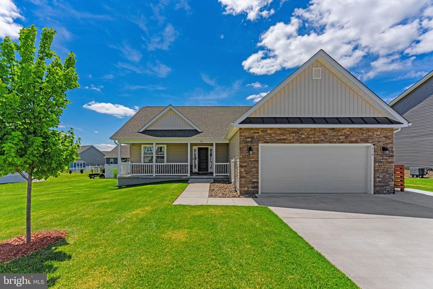 Built in 2022 and offering approximately 2,800 finished square feet, this spacious 4-bedroom, 3-bath ranch-style home in Heritage Hills subdivision offers modern comfort, flexible living space, and thoughtful seller upgrades. Designed for easy main-level living and built with durable 2x6 construction, the home is set on a .25-acre lot and features an open floor plan with vaulted ceilings, recessed lighting, a cozy natural gas fireplace, and luxury vinyl plank flooring throughout most of the home. A full front porch welcomes you home and offers the perfect spot to relax. Inside, the main level includes a bright living area, dining space, and a kitchen with granite countertops, a large island, stainless steel appliances, and a natural gas range, ideal for anyone who loves the precision and ease of cooking with gas. The primary suite features tray ceilings, a large walk-in closet, and a private bath with tiled shower. Two additional bedrooms and a full bath complete the main level. The finished lower level adds valuable flexibility with a large recreation area, fourth bedroom, full bath, kitchenette with sink and stove, upgraded flooring, and walk-up stairs to the backyard. Step outside to a fully fenced backyard with 6-foot white vinyl fencing and double gates, professionally landscaped with a lush, established lawn, mature trees, and a vegetable garden.  An expanded concrete driveway out front provides ample parking. Additional features include natural gas heat and a 2-car insulated garage with built-in shelving. Located in Martinsburg with convenient access to commuter routes, the MARC train, medical centers, and nearby educational options, this well-maintained Heritage Hills home offers space, comfort, and convenience inside and out.
