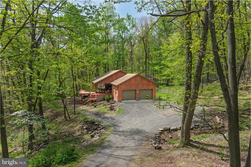 Price improved! Well maintained custom-built  cedar-sided mountain getaway on 2.2 secluded, peaceful acres. This 2-bedroom 2-bath home boasts a den and open-concept living room-kitchen-dining room area with plenty of natural light. Hardwood floors and Berber carpet throughout. Relax in front of the wood-burning stove and watch the wildlife from every window. Deer and wild turkey are frequent visitors. Intermittent spring borders edge of property. Wrap-around deck with outdoor shower perfect for sunbathers or avid gardeners. Electric hookup for motorhome on property. Spacious, full unfinished basement. Two-car garage and  expansive gravel driveway, offering plenty of room for additional parking. Kitchen, den, and second bedroom freshly painted; vinyl plank flooring recently installed in secondary bathroom. Furnace one year new.  Champion Dual Fuel 9000 Peak Watt Propane/Gas Generator and propane wall heaters in basement and garage convey. Annual memberships can be purchased for access to adjacent Avalon Resort, which features vacation condos, lodge, and an aquatics center. Just two hours from DC area, 40 minutes from fabulous shopping and restaurants in Winchester, VA, and 30 minutes to the historic spas of Berkeley Springs, WV. This home is part of a family-friendly clothing optional community. Come check out this unique property on Pendragon Court and find out precisely why West Virginia is considered "Almost Heaven."