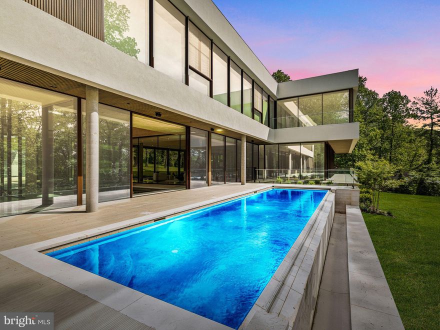 Among first impressions, "This is the finest home ever designed on the Main Line."  A striking 16,000-square-foot statement piece, The Glass House pushes the boundaries of contemporary luxury. Crafted by two visionary architects from Paris, this extraordinary home is a masterful fusion of glass, stone, wood, and steel—thoughtfully integrated into a landscape of mature trees and artfully designed gardens. Tucked away into the greenery overlooking Philadelphia Country Club, the Glass House offers unmatched luxury and privacy. Step inside to discover an interior where design and function are in perfect harmony. A dramatic two-story atrium greets you with an indoor pool as its centerpiece—an awe-inspiring focal point that offers both beauty and year-round enjoyment. The entire first floor is wrapped in warm-toned, large-format stone imported from India, creating a seamless sense of scale and flow throughout the living spaces. Floor-to-ceiling retractable glass panels erase the divide between inside and out, immersing the home in the beauty of its landscaped grounds and infinity-edge pool. At the heart of the home, a striking open-concept kitchen features deeply stained custom wood cabinetry, a massive center island with prep sink and integrated six-burner gas cooktop, sleek appliances and custom shelving. An adjacent indoor atrium brings life and freshness to the space, marrying nature and modernism. Perfectly curated for both grand entertaining and intimate daily living, the first floor is highly amenitized including the indoor pool, huge sauna, stadium tiered home theater and access to the Glass House grounds, which include another outdoor infinity pool. The home offers five luxurious bedroom suites, including a spacious main-level suite—while additional square footage provides the flexibility to create several more bedrooms if desired. The second level is accessible by one of two striking glass and white oak floating staircases, each suite serves as a private retreat, featuring oversized custom closets, Porcelanosa tile bathrooms, and peaceful balconies with views of the surrounding grounds. From the resort caliber amenities to its globally inspired architecture, The Glass House stands in a class of its own. Every inch of this residence reflects an uncompromising commitment to design excellence, craftsmanship, and serenity. Whether hosting unforgettable gatherings beneath the stars or enjoying quiet moments surrounded by nature, this home offers an unparalleled lifestyle experience. Truly, there is nothing else like it on the Main Line. For the discerning buyer who demands the extraordinary ---- Welcome Home.