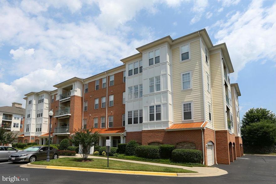 Lovely 2 BR/2 BA Kentlands luxury condo in elevator bldg. 4th floor corner unit w/ hardwood floors, 9 ft ceilings, recessed lighting, FP, custom paint & crown molding. Open floor plan w/ Living Room, Separate Dining Room, Kitchen w/ granite counters, breakfast bar, access to balcony overlooking trees. Owner's Suite w/ 2 closets, Full BA. 1 car garage. Laundry in unit. Close to shops/restaurants.