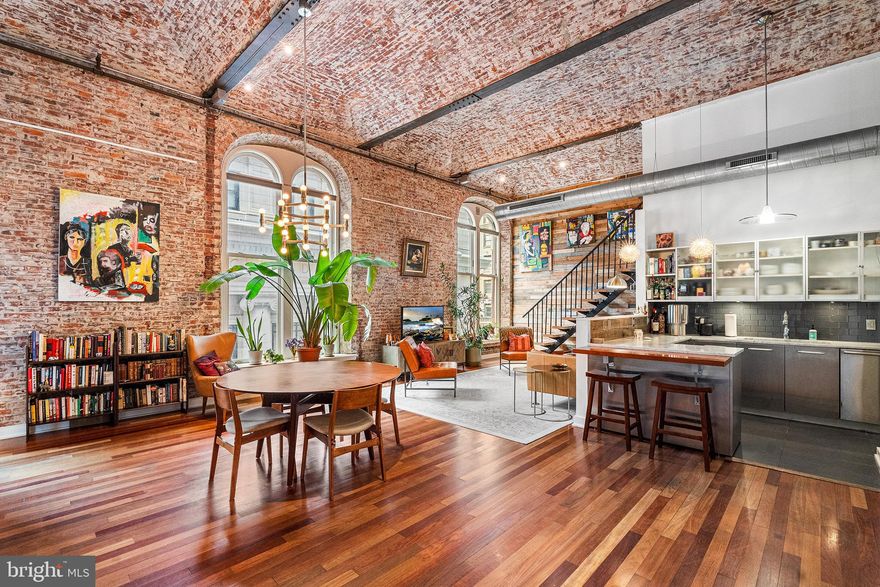 Residence No. 302 at The White Building is a one-of-a-kind loft set in one of Philadelphia’s most beloved neighborhoods and located within the McCall School Catchment. Originally constructed in the late 1800s as a factory, the building has been thoughtfully transformed into luxury loft residences that seamlessly pair its historic, pre-war character with refined modern living. With preserved barrel-vaulted ceilings, dramatic brick walls, and arched windows, the building’s original character reveals itself at every turn. A central living room welcomes upon arrival and frames direct views of a neighboring Horace Trumbauer building. The wide living room is positioned at the front of the condo and flows into a kitchen featuring an island with seating, a Carrara marble countertop, stainless-steel and frosted-glass cabinetry, and a row of appliances flush with the cabinets. Opposite the Sub-Zero refrigerator, Bosch dishwasher, induction cooktop, and wall oven are tall cabinets that serve as convenient pantry storage. A laundry closet with a front-loading washer and dryer is accessed via a pocket door at the back of the kitchen. The spacious dining area is steps away, beneath a Sputnik chandelier. Gracious closet space as well as a full tiled bathroom with a soaking tub and modern vanity complete the open entertaining area—and make hosting a breeze. The primary bedroom is located off the living room; it’s open and airy, with the same wood flooring that continues throughout. The view from the two oversized windows is teriffic as well. With a spacious walk-in closet and an en-suite bathroom complete with a glass-framed shower, a wide contemporary vanity, and river rock tiling, the king-size primary suite was thoughtfully designed and is a tranquil space to begin and end each day. An additional loft space is accessed via a custom staircase in the living room. The loft is the perfect workspace, music room, or sleeping quarters for guests! A nook beneath the stairwell offers a great space for a console or record player. This captivating property is also smart, with tech upgrades like Lutron Caseta lighting, electronic blinds, a Nest Thermostat, and keyless entry. The property additionally features mirrored windows for privacy and an acoustic door seal for added sound insulation! The White Building is a favorite among architecture buffs and a sought-after condominium in Washington Square West. The community offers keyless entry, an in-building fitness room, recent common area improvements, including HVAC upgrades, a secure mail room, and coded elevators. Residents love the proximity to some of the area’s best restaurants, cafes, shops, and gyms. Washington Square West and Midtown East are served by multiple grocers, like Mom’s Organic Market, Trader Joe’s, and the Reading Terminal Market. City Fitness, Rival Bros, Pressed Juicery, and Starbucks are among the countless local and big-box shops that call this neighborhood home. We look forward to showing you all that this incredible property has to offer. Disclaimer: Tax amounts and square footage data are to be verified by the buyer and buyer’s agent, as these are not guaranteed by the listing brokerage, broker, or licensee. The square footage estimate is inclusive of the upper loft.