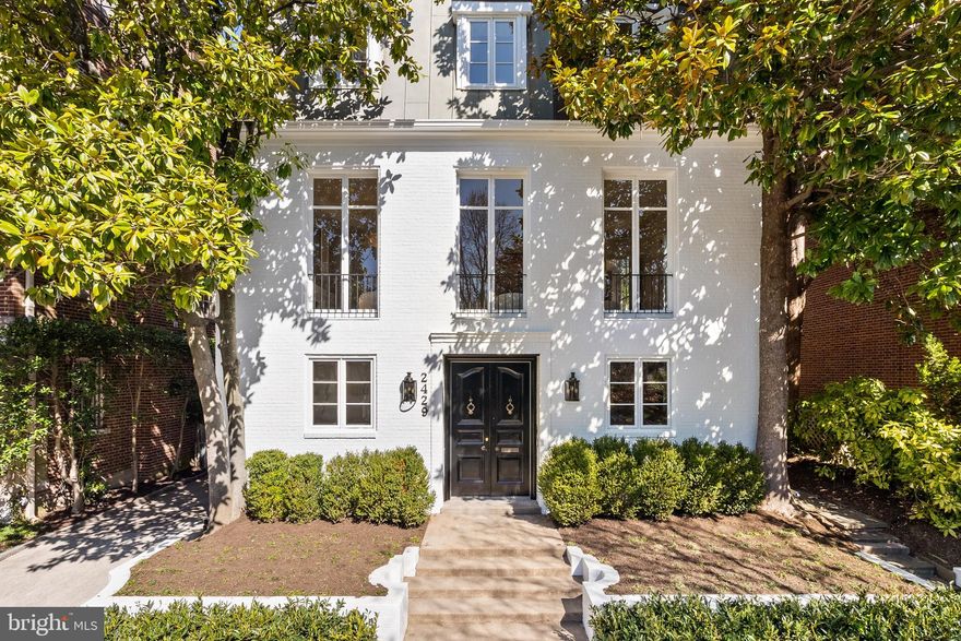 Nestled in one of Washington, D.C.’s most prestigious enclaves, this exquisite French Mansard-style residence in Kalorama offers a rare blend of elegance, tranquility, and urban accessibility. Set on a quiet, tree-lined street, this detached home is an entertainer’s dream, with grand yet inviting spaces that seamlessly balance refined sophistication and modern comfort. With 4,752 square feet of meticulously curated interiors, and a design-focused renovation led by Tays & Co., this residence represents the pinnacle of Kalorama living.

Enter through solid oak French doors, appointed with ornate brass hardware, into a gracious foyer accented by marble flooring, custom lighting, and traditional wall moldings. The first floor hosts two bedrooms and two full bathrooms, a laundry room, and garage access, providing a functional yet luxurious entry into the home. A striking curved staircase at the home’s central core guides you to the main entertaining level, while an elevator services all three levels. 
The south-facing great room, spanning the width of the home, is drenched in natural light from several Juliet balconies. Featuring a wood-burning fireplace with a marble surround, custom lighting, traditional wall moldings, and oak hardwood flooring, this space is both elegant and inviting—perfect for intimate evenings or grand entertaining.

On the west side, the impeccable kitchen is a masterpiece of craftsmanship. Custom cabinetry, an oversized island, and a built-in banquette are accented with Arabescato D’Oro marble, while top-tier appliances—including two dishwashers, dual wall ovens, a beverage center, ice maker, and coffee bar—ensure seamless functionality. A hand-plastered custom range hood serves as the room’s sculptural centerpiece. Adjacent, the formal dining room and kitchen both offer access to the secluded backyard, an idyllic setting for al fresco dining and entertaining beneath the canopy of a majestic Heritage oak.

Ascending the central core staircase, illuminated by a 20-foot wall of windows and a custom chandelier, the third floor is a private sanctuary. The primary suite is a study in sophistication, centered around a wood-burning fireplace and featuring intricate herringbone oak flooring. The spa-like ensuite bath is adorned with a dual vanity topped with Naica quartzite, a freestanding soaking tub, and a handcrafted Zellige tile shower, leading to a spacious dressing room with custom closet cabinetry and a makeup vanity.

The junior suite overlooks the serene backyard, offering a tranquil retreat with custom Australian wool carpeting. Its ensuite bath, clad in travertine and accented by a glass-enclosed shower, is complemented by a walk-in closet with custom built-ins.

A distinguished neighborhood offering peaceful seclusion, yet just moments from Dupont Circle, Georgetown, and Embassy Row, this home is a rare opportunity to experience timeless elegance and contemporary luxury in Washington’s most coveted enclave.