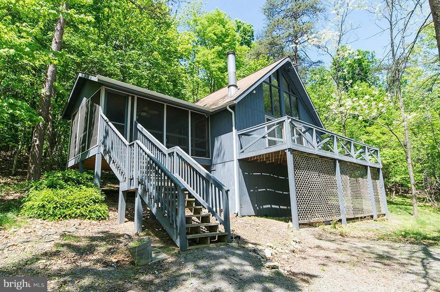 Cabin in The Woods   Sit on your wrap around deck and watch the leaves change, watch the deer and wild turkey stroll across the almost 1 acre lot.  Lie in bed at night and watch the moon come up above the trees and have the sun wake you in the morning as it rises. Have you morning coffee on the screened in porch or the wrap-around deck.   All of this only an hour and a half away from the DC beltway in The Woods Resort in Hedgesville, WV.  The Popular Elmwood model is situated on a wooded site. Beautiful window wall of glass in the great room with cathedral ceilings, fireplace with wood stove to keep you warm in the Winter or cool Fall nights, newer carpet and flooring in kitchen and bathroom.  Sliding glass doors to wrap around open deck.  One BR + loft + full bath on main level.  Screened in porch with vaulted ceiling & ceiling fan/light.  Heat pump with central air/heat, new installation and new heat tape on pipes.   Indoor/outdoor membership is available with $3150 initiation fee.  Priced to Sell!!!
