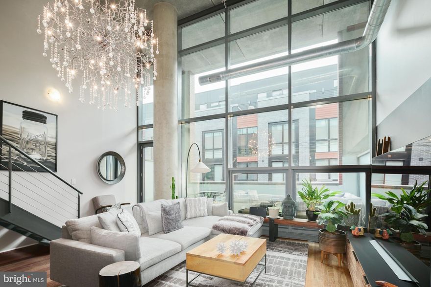 Modern 1 bedroom, 2 full bathroom bi-level loft condo featuring a large open floor plan in the heart of the Avenue of The Arts! Upon entering this meticulously maintained residence, one is immediately impressed by the expansive 20-foot floor-to-ceiling windows that provide an abundance of natural light. The open living area on the main floor is adorned with exquisite hardwood flooring throughout, a full bathroom ideal for guests, and a distinguished chandelier that enhances the uniqueness of the space. The fully equipped kitchen, complete with a large breakfast bar, granite countertops, and ample storage, offers a perfect setting for entertaining. The Southern exposure allows for plentiful light through the floor-to-ceiling windows, featuring motorized shades that cover the entire front of the unit. Adjacent to the living area, there is a spacious private balcony ideal for outdoor dining and gardening. The custom floating staircase leads to an oversized bedroom that provides a view of the expansive living area below. The large walk-in closet features custom built-in storage and accommodates full-sized laundry facilities discreetly tucked away. The property also includes a substantial fully tiled ensuite bathroom equipped with a large walk-in shower and an updated vanity—an essential feature. The intricate details and finishes of this home will surpass your expectations for loft living. On-site parking can be rented or purchased separately, subject to availability. Located centrally with 24-hour concierge, pet-friendly policies and two elevators. Steps from top Philadelphia restaurants, shopping, and theater, including Last Drop Coffee house, Del Frisco's Grille, Steak 48, Giorgio on Pine, Loch Bar restaurant and Whole Foods. The property offers convenient access to public transportation, including the Broad Street line and SEPTA bus routes. Additionally, it is just minutes away from sports arenas and major highways such as I-76 and I-95.