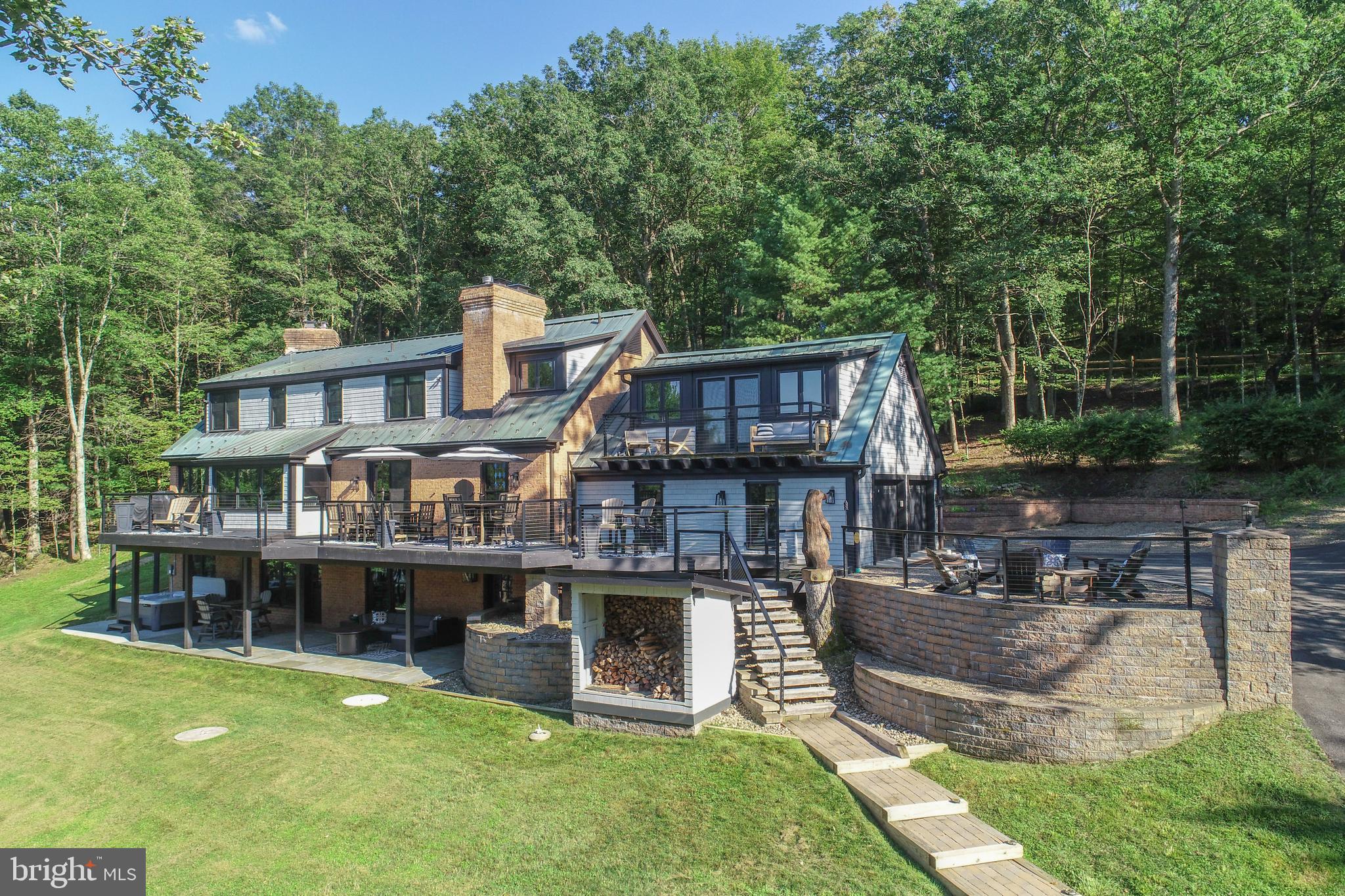 Step into a home like no other—where architectural charm meets modern comfort, and lake views greet you from nearly every room. With six bedrooms and five-and-a-half baths, there’s space for everyone to relax in style. The open, light-filled main living area is anchored by a striking fireplace and a window-wrapped dining alcove with serene water views, while a wall of windows frames the gorgeous kitchen at one end. Off the open living/dining/kitchen area, you’ll find a second living space, perfect for intimate gatherings or quiet reading. The sunlit study is a dream, with floor-to-ceiling windows and skylights that bring the outdoors in.
The spacious lakeside main-level primary suite features its own fireplace, and charming bath with a walk-in shower and double sink and vanity area, and closet area with built-ins. It is a wing onto itself for optimal privacy.
Their is a second primary suite upstairs offers a private retreat with a charming tiled bath, and windowed walk in closet. Every spacious bedroom has its own personality—two have private decks for morning coffee or evening sunsets. Two wonderful baths complete the upstairs.
On the lower level, fun is the theme: a huge family room with pool table, game-night or movie area, and a stunning bar with its own TV. A full bath, generous storage area, and a mudroom for coming in from the lake, make it as practical as it is inviting.
Outside, the property truly shines. This private 1.13-acre lot boasts a rare 250 feet of level lakefront, an oversized covered dock with two jet ski slips, and a charming lakeside shed. A full-length deck spans the main level, with a built in firepit overlooking the lake and stars at night. While the patio on the lower level includes a hot tub area—perfect for soaking in the views. For your cars there is a two-car attached garage plus a beautiful, separate oversized three-car garage for all your lake toys!
Completely remodeled in 2020—including all-new windows—this rare lakefront property is located in the exclusive Pergin Farm area of Deep Creek Lake. This special property is ready to impress from the moment you arrive. Whether you’re hosting friends and family, enjoying quiet moments, or spending sunny days on the water, this home delivers the ultimate blend of style, comfort, and recreation.