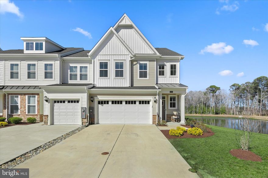 Welcome to 31023 Nikelle Lane, a beautifully appointed end-unit townhome in the desirable community of Milos Haven—where tranquil pond views, modern design, and coastal convenience come together perfectly. Built in 2023 and presenting like new, this exceptional residence is ideally located just six miles from the vibrant seaside town of Bethany Beach, its beloved boardwalk, and miles of pristine Delaware coastline. Tucked quietly at the end of a cul-de-sac and positioned beside a scenic pond preserve, this home enjoys a setting that feels peaceful and private, with serene water views providing the perfect natural backdrop.
Step through the covered entry into a bright and welcoming interior featuring a freshly painted palette, abundant natural light, and wide-plank luxury vinyl flooring throughout the main level. The open-concept design makes everyday living and entertaining effortless. At the heart of the home, the well-appointed kitchen is both stylish and functional. It showcases gleaming Quartz countertops, a spacious island with seating, a pantry, and a suite of stainless steel appliances including double wall ovens, a gas cooktop, microwave, dishwasher, refrigerator, and hood vent, all complemented by recessed lighting and thoughtful design. Just beyond the kitchen, the dining area and living room flow seamlessly together, creating an inviting space for gathering with family and friends. Sliding glass doors lead to a private screened porch overlooking the tranquil, tree-lined pond, an idyllic setting for morning coffee, evening cocktails, or peaceful moments surrounded by nature. Upstairs, a spacious family room anchors the bedroom level, offering a flexible space for relaxing, movie nights, or quiet reading. The primary suite serves as a true retreat, featuring a generous walk-in closet and a stylish ensuite bath with dual vanity, private water closet, and a beautifully tiled shower with built-in bench seating. Two additional bedrooms share a well-appointed hall bath, while a convenient laundry room with utility sink completes the upper level. Additional highlights include a two-car garage finished with drywall and paint, along with a driveway offering parking for up to four vehicles, ideal for hosting guests. As an end-unit residence located on a quiet cul-de-sac and bordered by a scenic pond preserve, this home enjoys added privacy and picturesque surroundings that enhance everyday living. Whether you’re seeking a full-time residence, a coastal getaway, or an investment opportunity, 31023 Nikelle Lane offers a wonderful blend of modern comfort, natural beauty, and proximity to everything the Delaware coast has to offer.