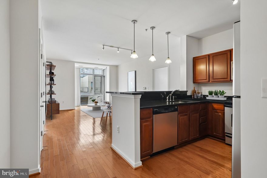 Step into modern urban comfort with this impeccably located 2-bedroom, 2-bathroom condo in the heart of Hyattsville’s most vibrant district. This home features a bright, open-concept main living area highlighted by gleaming hardwood floors and a layout designed for both relaxation and entertaining. The updated kitchen is as functional as it is stylish, boasting stainless steel appliances, ample cabinetry, and soft track lighting that creates a warm, inviting ambiance. The integrated eat-in counter provides the perfect spot for quick morning coffee or casual meals. For those who crave a bit of nature, the unit offers two distinct retreats: a charming bump-out window cove ideal for a lush indoor garden or reading nook, and a private balcony perfect for evening relaxation.
The living quarters are designed for privacy and convenience, with carpeting in both bedrooms. Each bedroom features its own generously sized en-suite bathroom, making this an ideal setup for roommates or guests. Beyond the front door, you are immersed in an array of amenities. Located less than one mile from the Metro, across the street from a Regal movie theater, with blocks of diverse dining options and local boutiques, the best of this walkable suburban enclave is at your fingertips. With the Mall at Prince George’s only one block away for all your shopping essentials, this condo offers the perfect blend of suburban convenience and urban flair.