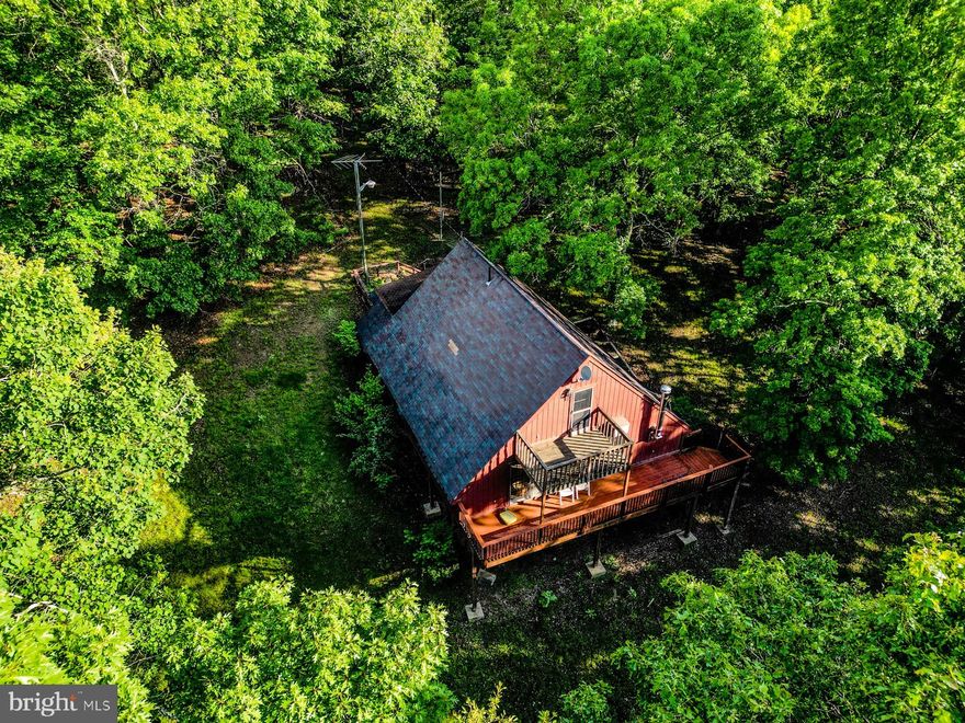 Tucked away in the mountains of Great Cacapon, WV, this chalet-style retreat offers a rare mix of privacy, potential, and freedom—whether you're looking for a peaceful weekend getaway, a future retirement spot, an Airbnb income property, or your own mini homestead.

Situated on 6.21 mostly flat, usable acres with no HOA, this 1,638 sq ft. cabin is fully furnished, move-in ready, and full of possibilities. While it does need some TLC, that just means you can customize renovations to make it your own—whether you're after rustic charm, modern upgrades, or a cozy combo of both. You have the freedom to make it your own!

Inside, you'll find 2 bedrooms and 2 full bathrooms—one on each level. The main floor bedroom is just steps from a full bath, while the upstairs offers another bedroom and bathroom with a loft space perfect for an office, reading nook, or extra sleeping area. Natural light pours through two sets of French doors, and a pot belly wood stove adds warmth and character to the open living space. The sellers will not entertain repair negotiations, Sold as-is.

Enjoy the outdoors from your screened-in porch, large back deck with mountain views, and even an outdoor shower—perfect after a day of adventure. The land is ideal for those dreaming of a homesteading lifestyle, with plenty of level space for gardens, goats, chickens, horses, or other livestock, and a gentle slope toward the back of the property.

Located just 10 minutes from public Cacapon River access for fishing, swimming, and kayaking, and 10 minutes from a local brewery and winery—you’ve got both serenity and small-town fun at your fingertips. Outdoor lovers will appreciate the nearby Cacapon Resort State Park, while those craving more culture or shopping can head to Berkeley Springs (20 mins), Winchester, VA (1 hr), or Martinsburg, WV (just over an hour).

No HOA! Hunting, shooting, ATV's allowed. Whether you're starting a homestead, launching a short-term rental, or looking for a mountain place to make your own, this property is ready for its next chapter—and it could be yours.