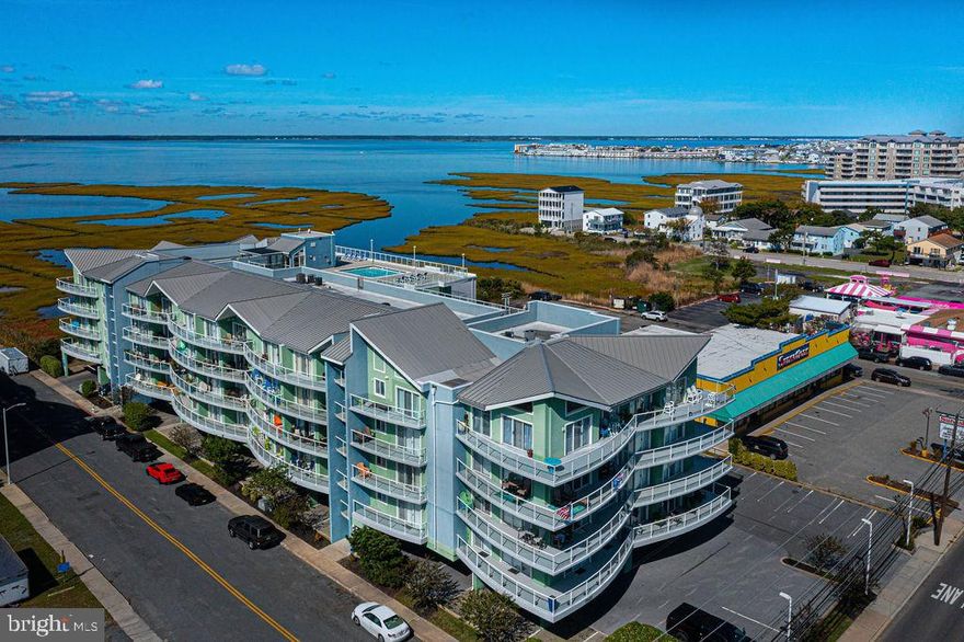 Bright and Sunny mid-town  furnished condo with easy access from Rt 90!  The top floor corner location provides you with a huge wrap-around balcony offering expansive bay views, gorgeous sunsets, and even a bit of the ocean!  A corner electric fireplace offers ambience in the living area.  You'll be happy to cook in this kitchen with Stainless appliances, Granite Countertops, Breakfast Bar, and Embossed metal panel ceiling. Features include Vaulted Ceilings, Luxury Vinyl Plank Flooring, Crown Molding, Chair Rail, Pocket Doors,  and a security system.  Two separate impressive primary suites with balcony access, tile-surround whirlpool tubs, tray ceilings, and separate  tiled showers.  Amenities include a rooftop pool and sundeck, exercise room, storage locker, 2 elevators, and under building parking.  Water Heater new in 2018, HVAC new in 2017, Washer new in 2023. Walk to the Atlantic Ocean, Dining, shopping and amusements!
