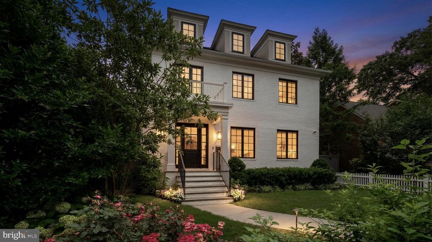 Set against the iconic backdrop of the National Cathedral in the heart of verdant Cathedral Heights, 3117 38th Street NW is a masterfully crafted modern farmhouse designed by GTM Architects in collaboration with MMg Development and built by Murillo/Malnati Homes. This distinguished team partnered with acclaimed landscape designer Lila Fendrick to deliver a residence that marries high design with luxurious livability, showcasing top-tier craftsmanship, seamless indoor-outdoor flow, and enduring style.

Completed in 2019, the home spans nearly 8,000 finished square feet across four thoughtfully designed levels. A white brick façade, black-trimmed windows, flagstone walkways, and manicured landscaping create timeless curb appeal. The front portico opens to a gracious foyer with sightlines that extend to the rear terrace, setting a tone of openness and elegance. Crown moldings, gleaming hardwood floors, and abundant natural light provide a sophisticated yet welcoming atmosphere.

The formal living room, with a gas fireplace and custom built-ins, overlooks the front garden. A tray ceiling and wainscoting in the adjacent dining room elevate formal gatherings. A marble-clad butler’s pantry with a beverage fridge connects seamlessly to the chef’s kitchen, which features custom stacked cabinetry, Wolf and Sub-Zero appliances, a full-height marble herringbone backsplash, and an expansive island with bar seating.

The open-concept kitchen and adjoining family room serve as the heart of the home. Coffered ceilings, a marble fireplace, and dual sets of French doors open to a flagstone terrace beneath a full-width pergola, perfect for indoor-outdoor entertaining and framed by views of the Cathedral.
Additional main-level features include a custom mudroom with built-in cubbies and side entry, access to a detached two-car garage with EV hookup, and a large walk-in pantry. A powder room and elevator complete this level.

Upstairs, the primary suite occupies its own wing and includes a private rear deck with cathedral views. The spa-inspired primary bath features radiant heated marble floors, a freestanding soaking tub, a glass-enclosed shower, a wall-spanning double vanity, and a private water closet. A custom dressing room with golden backlit shelving and abundant storage completes the suite. Three additional bedrooms, one currently used as a home office, share two full bathrooms along with a large, fully equipped laundry room.

The third level offers flexible living with two additional bedrooms, one styled as a game room with alcove seating, and a full bath. This space is ideal for guests, teens, or creative pursuits.

The finished lower level includes high ceilings, a recreation room with integrated Sonos sound, a wet bar with a Sub-Zero beverage fridge, a custom wine room, a fitness studio, a powder room, and a second laundry area. A private guest or au pair suite features a kitchenette, bedroom, and full bath.

Smart home systems include Legrand lighting, Honeywell Pro Series thermostats, integrated security with cameras and motion sensors, and multiple wall-mounted iPads for controlling lighting, sound, and surveillance.

Outdoors, a flat, professionally landscaped lawn is pool-ready and features a built-in grilling station, an extensive stone terrace, ambient lighting, irrigation, and French drainage systems for year-round enjoyment.
Steps from Massachusetts and Wisconsin Avenues, this premier location offers proximity to top-rated schools, lush parkland, and downtown DC. Elegant yet approachable, richly appointed yet supremely functional, 3117 38th Street NW is a rare offering that defines modern luxury living in Washington.