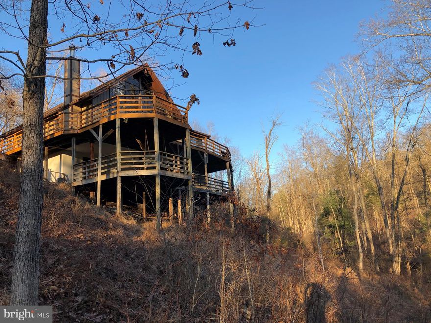 Looking to get away from it all?   Want a secluded property?    Come see this affordable fully furnished mountain retreat! New Septic System in place. Three bedrooms in main house with bonus room in basement separate from laundry. The main house offers incredible floor to ceiling windows and extensive decking overlooking your very own dock and pond.   Overtop of the 2 car garage is a separate income producing 1BR 1BA apt or in-law suite. Do you like to work with your hands you ll love the separate workshop with electricity!  And don't miss the large laundry area and hidden office or sewing/craft room beneath the main house.  And, an extra lot at the top of the drive.  All of this on 7+ acres less than 20 min to town.  Would make fabulous Airbnb /Second Home/ Small Retreat Center or even just a great Retirement property for those who aren't quite ready to just sit still yet!   Yes....all furnishings included.  Don't miss this rare opportunity!    Schedule your showing today!  Property has HOA.   Sorry no gun berms allowed.  COME SEE! All sz approx.