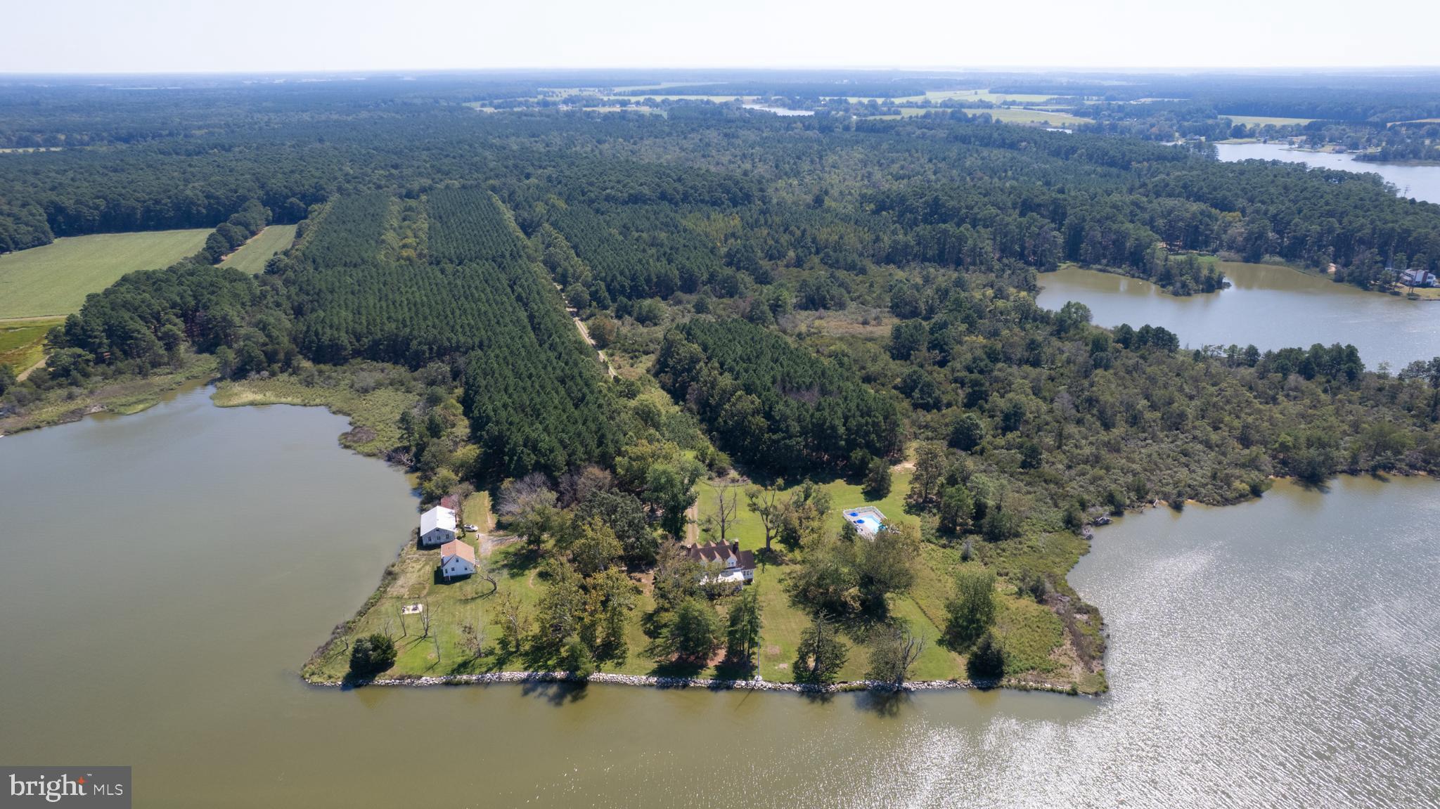 Step into the elegance of a 50-acre waterfront estate steeped in timeless charm. Built in 1920, this Neo-Classical Eastern Shore property offers the perfect combination of sophistication and natural beauty. The property is awaiting the perfect buyer who can transform it back to the style and charisma of it's earlier days.
Enjoy a bright, welcoming interior. The main house features a large center hall foyer that leads to a stunning living room with a brick fireplace, custom-built shelving, and dual French doors opening into a sunroom. Bask in serene waterfront views from the sunroom, complete with hardwood flooring and another brick fireplace—a space designed for entertaining or quiet retreats.
Create unforgettable dining experiences in a formal dining room highlighted by Black Walnut paneling, tasteful wall sconces, and a custom-built wine glass cabinet. The enclosed side porch, fitted with vintage touches like brick flooring, laundry amenities, and the original farmhouse enamel sink, doubles as a mudroom. Meanwhile, the waterside screened porch invites al fresco dining with picturesque views of Church Creek.
The second floor offers practicality and comfort with four bedrooms and two bathrooms, accommodating family and guests with ease. A walk-in cedar lined closet and another walk-in attic closet offer a surprising amount of storage.
Enhance your lifestyle with additional perks. A thoughtfully updated guest cottage (2019) offers two bedrooms, one bathroom, a kitchen, a living room, a dining area, and laundry facilities—currently enjoyed as a vacation rental. Wildlife thrives here: expect visits from ospreys, bald eagles, and white-tail deer in an atmosphere guests rave about.
Relax poolside with a redesigned in-ground pool (2022) boasting a paver deck, modern landscaping, and fencing—all with views of Church Creek. A 28 x 42 wooden barn with concrete flooring, with space sufficient for garage/vehicle or boat storage, and an upper story is complemented by a four-stall stable and additional sheds. The barn built in 1960 was built using reclaimed wood from old chicken houses.
Environmental stewardship defines this property. Placed in an Environmental Trust, the land remains protected, ensuring its use promotes nature and agriculture. Boating lovers will appreciate the creek’s access to the Chesapeake Bay, renowned for crabbing, fishing, kayaking, and paddle boarding.
Let your vision breathe life into this stunning space. This estate pairs historical allure with limitless possibilities for those ready to turn dreams into reality.