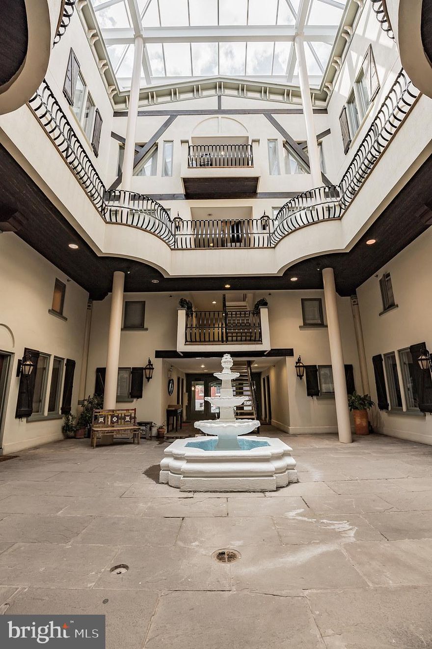 Welcome to The Carriage House, where historic charm meets modern comfort. This light-filled condo with loft and one car parking offers a prime location within walking distance of shopping, restaurants, Fairmount Avenue, the Art Museum, Kelly Drive, and public transportation, including the Broad Street Line. The handsome brick building showcases a stunning glass atrium complete with a tranquil water fountain. Step inside unit 110 to discover an open-concept living area featuring gleaming hardwood floors, recessed lighting, and two oversized south-facing windows that flood the space with natural light.
The inviting living/dining area offers ample room for entertaining or enjoy a casual meal at the breakfast bar illuminated by stylish pendant lighting. The gorgeous kitchen boasts granite countertops, rich wooden cabinetry with crown molding, stainless steel appliances, and a custom tile backsplash. A bonus storage space works great for a large pantry or coat closet. Follow the spiral staircase to the bright, loft-style bedroom featuring exposed beams and generous closet space with built-in shelving. The spacious full bathroom is beautifully tiled and includes a large vanity with abundant counter space, plus a stackable washer and dryer for added convenience. Leave the car in your gated assigned parking spot and enjoy exercising your green thumb at the Spring Garden Community Garden, bars and restaurants along Fairmount Avenue and of course the iconic Eastern State Penitentiary. You’re also minutes from Boat House Row, Kelly Drive, Schuylkill River Trail, plus all the art and Culture lining the Parkway.  Experience all that Fairmount has to offer from this truly distinctive condo in a pet-friendly building!