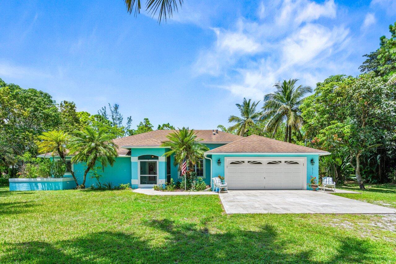This immaculate 3-bedroom, 2-bathroom pool home offers a spacious, bright split floor plan and sits on nearly 1.5 acres of land. Privately located in The Acreage, it's surrounded by lush landscaping and bordered by water on the west and north sides.A brand-new, powered outdoor shed adds extra convenience. The kitchen is equipped with a gas range, stainless steel appliances, and an eat-in area that opens into a cozy family room with a beautiful stone fireplace. The home features high vaulted ceilings, arched windows, recessed lighting, and plantation shutters throughout. The interior has been freshly painted as well.The backyard is perfect for entertaining, with a screened-in pool featuring a waterfall and a spacious covered patio.