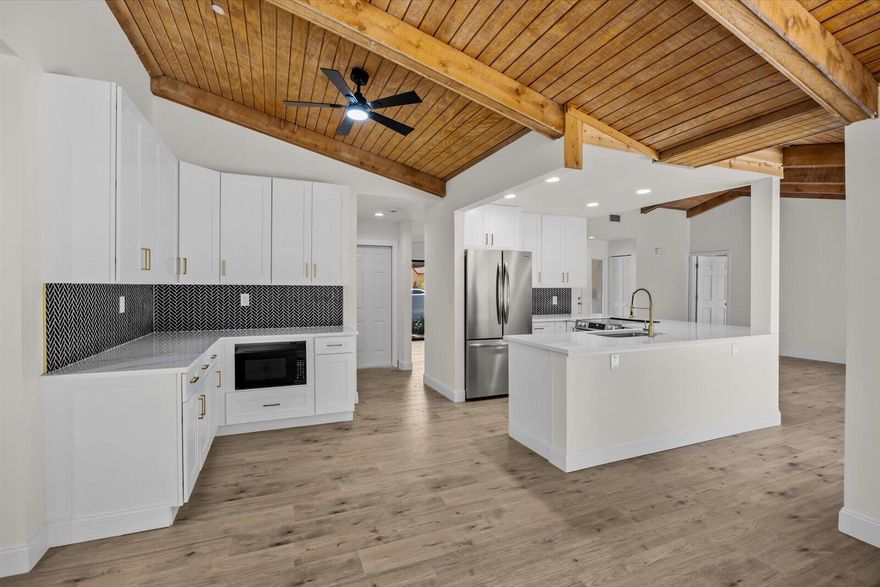 Exquisite 3-bedroom, 2-bathroom residence, fully renovated in 2026. High ceilings compliment this wide open gourmet kitchen boasting luminous Calacatta quartz countertops, bespoke soft-close shaker cabinetry, and premium high-end finishes. Luxurious spa-inspired bathrooms feature sophisticated tile work, gorgeous vanities, and contemporary fixtures, elevating daily rituals to a serene escape. Impeccable waterproof laminate flooring, freshly painted interiors and exteriors, and brand-new, top-tier appliances blend style with functionality. Outdoor living space with inground pool to enjoy Florida's year round lifestyle.  This residence seamlessly blends modern luxury with timeless comfort. New Tile Roof 2026!