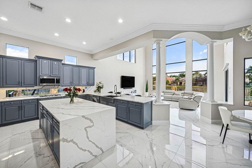 European elegance meets modern sophistication in this exquisitely updated Marseilles estate, ideally positioned on a quiet 17,000 sq ft cul-de-sac lot with sweeping lake views in Versailles. Soaring ceilings, dramatic windows, and polished Italian porcelain tile create a breathtaking first impression, with panoramic views of the resort-style pool and water beyond. Offering over 6,300 square feet, this thoughtfully designed home features 5 bedrooms, 6.5 baths, a private office, loft, media theater, and oversized 3-car garage. The stunning gourmet kitchen showcases waterfall quartz countertops, natural gas cooktop, double wall ovens, Miele built-in coffee system, custom cabinetry, apron sink, and walk-in pantry -- all flowing seamlessly into the expansive family room and casual dining area filled with natural light and tranquil lake views. A grand formal dining room with adjacent bar elevates the home's entertaining appeal. The first-floor primary suite is a private sanctuary with dual spa-inspired bathrooms, custom walk-in closets, a coffee bar, and serene sitting area with French doors overlooking the pool and preserve. A top of the line Michael Phelps therapeutic spa completes the resort experience. A guest suite, private office, and additional powder bath are also located on the main level. Upstairs offers three spacious bedrooms, three baths, an open loft, and a fully customized media theater room with acoustic walls, premium seating, and top-tier projection system for a true cinematic experience. The backyard is a private waterfront oasis featuring a saltwater pool with slide, new natural gas heater and pump, and a brand-new lakeside summer kitchen with grill, flat-top, refrigerator, beverage chiller, stone counters, sink, and two flat-screen TVs. An expansive travertine patio, outdoor sound system, LED lighting, and large fenced grassy area make this home ideal for entertaining or quiet evenings under the palms. Versailles residents enjoy 24-hour manned security, a renovated clubhouse, resort-style pool, fitness center, tennis and basketball courts, playground, and HOA-included lawn care, cable, and WiFi. Just minutes from Wellington's equestrian venues, International Polo Club, Whole Foods, Trader Joe's, fine dining, shopping, the Florida Turnpike, and PBI Airport. Meticulously updated and impeccably maintained -- this is luxury lakefront living at its finest.

Other updates and features:
Updated laundry room with new cabinets, counter tops and washer and dryer
4 newer 5-ton AC units (2022-2023)
Whole-house water filtration + reverse osmosis system
Full storm shutters
New Central vacuum
Smart doorbell and cameras
Updated sprinkler pump and irrigation
Wired for sound with outdoor speakers
New garage doors and openers
Newly finished garage floors
Remote control blinds in the family room
Plantation shutters in the Primary Bedroom and Bath