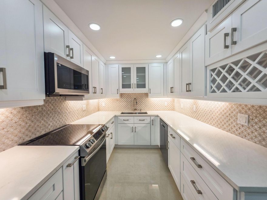 THE PINNACLE OF LUXURY IN PALM CLUB WEST! Prepare to be impressed by this meticulously redesigned 3-bedroom, 2-bathroom ground-floor residence, which has undergone a complete, high-end transformation. No expense was spared in this ''down-to-the-studs'' remodel, featuring impact-glass windows for ultimate peace of mind and energy efficiency. Step inside to find expansive high-end porcelain tile flooring that carries throughout the open-concept living space. The chef-inspired kitchen is a showstopper, boasting custom cabinetry, premium quartz countertops, and a suite of top-of-the-line appliances. Unlike standard units, this home features a rare, independent laundry room for maximum convenience and storage. Both bathrooms have been updated, featuring custom walk-in showers with designer tile work and luxury finishes. Nestled within a secure, gated community just minutes from The Square, PBI Airport, and the ocean, this property offers the finishes of a custom estate with the convenience of condo living. This is truly a one-of-a-kind unit that must be seen to be appreciated.