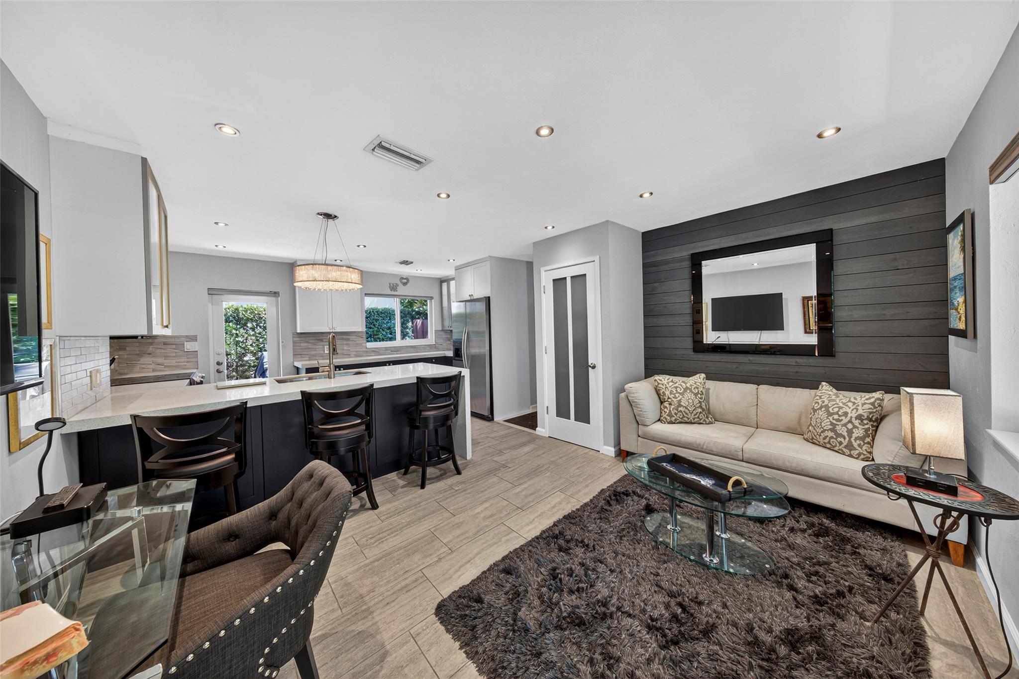 Move right into this beautifully updated and fully furnished 1-bedroom, 1-bathroom unit—complete with TVs, furnishings, and all essentials. Flooded with natural light, this modern space features sleek cabinetry, white quartz countertops with a waterfall edge, a custom backsplash, and stainless steel appliances. The bar counter offers seating space perfect for casual dining. Impact windows and doors throughout, all outfitted with new blinds, offer peace of mind and energy efficiency. Enjoy upscale tile flooring, a custom-tiled hallway, and a designer bathroom with a floating vanity and white countertop. Freshly painted with elegant custom wall panels and updated lighting throughout, plus central A/C for year-round comfort. This unit is in excellent condition and truly move-in ready.