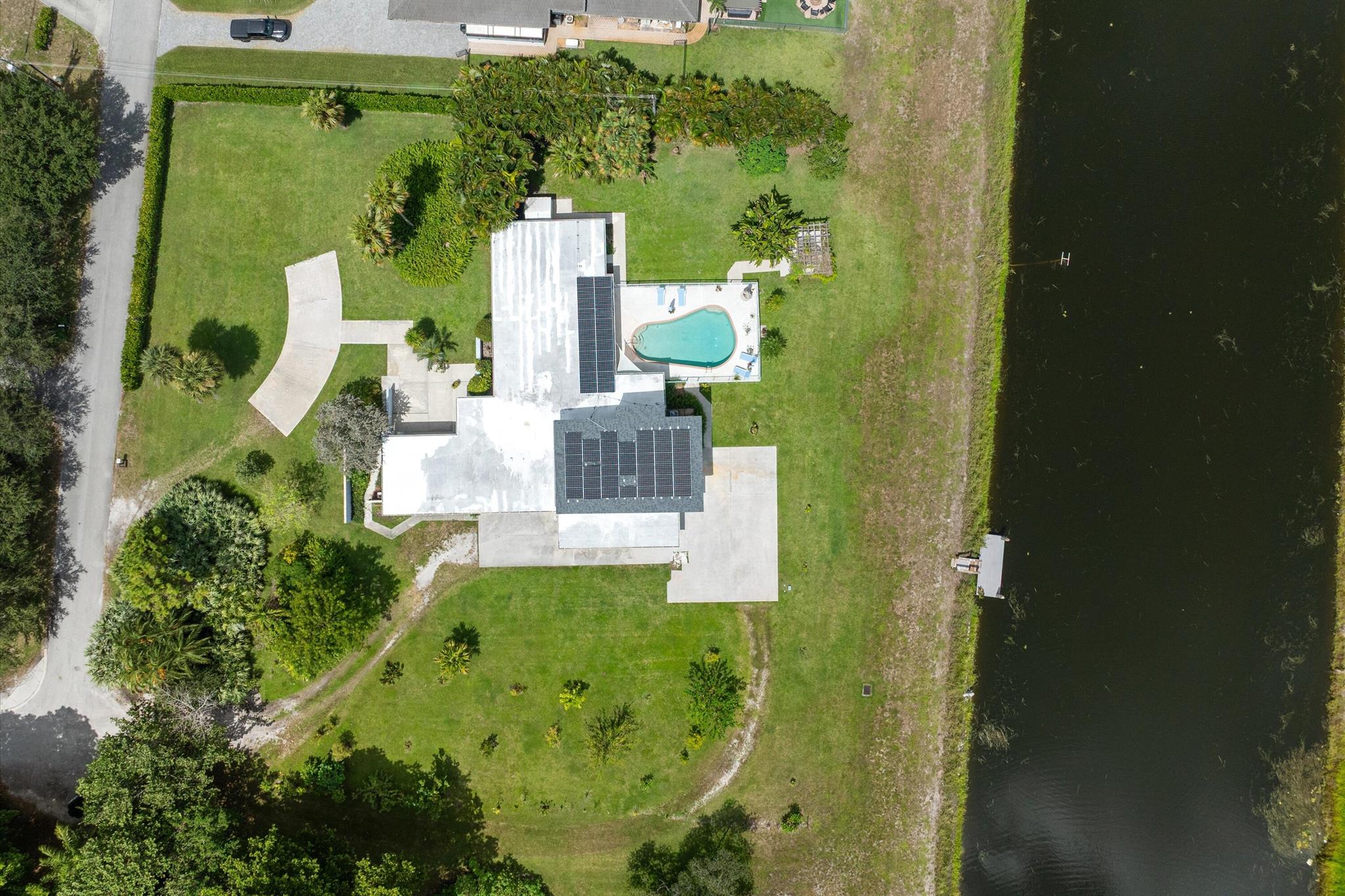 A true sanctuary designed by renowned architect Roy Simon, this vintage, sprawling home offers an extraordinary lifestyle wrapped in serenity and natural beauty. Tucked away on over 1.2 lush acres--including a newly granted .21-acre easement--this distinctive Delray Beach property blends timeless architectural detail with a Zen-inspired layout, creating a private retreat just minutes from the heart of the city.The main house features three bedrooms and two and a half baths across a generous single-level floor plan that flows effortlessly from space to space. A grand foyer sets the tone, leading into an oversized living room with custom barn doors and exposed wood-beamed ceilings--a signature of Simon's design. Original Dade County pine floors and tongue-and-groove ceilings infuse